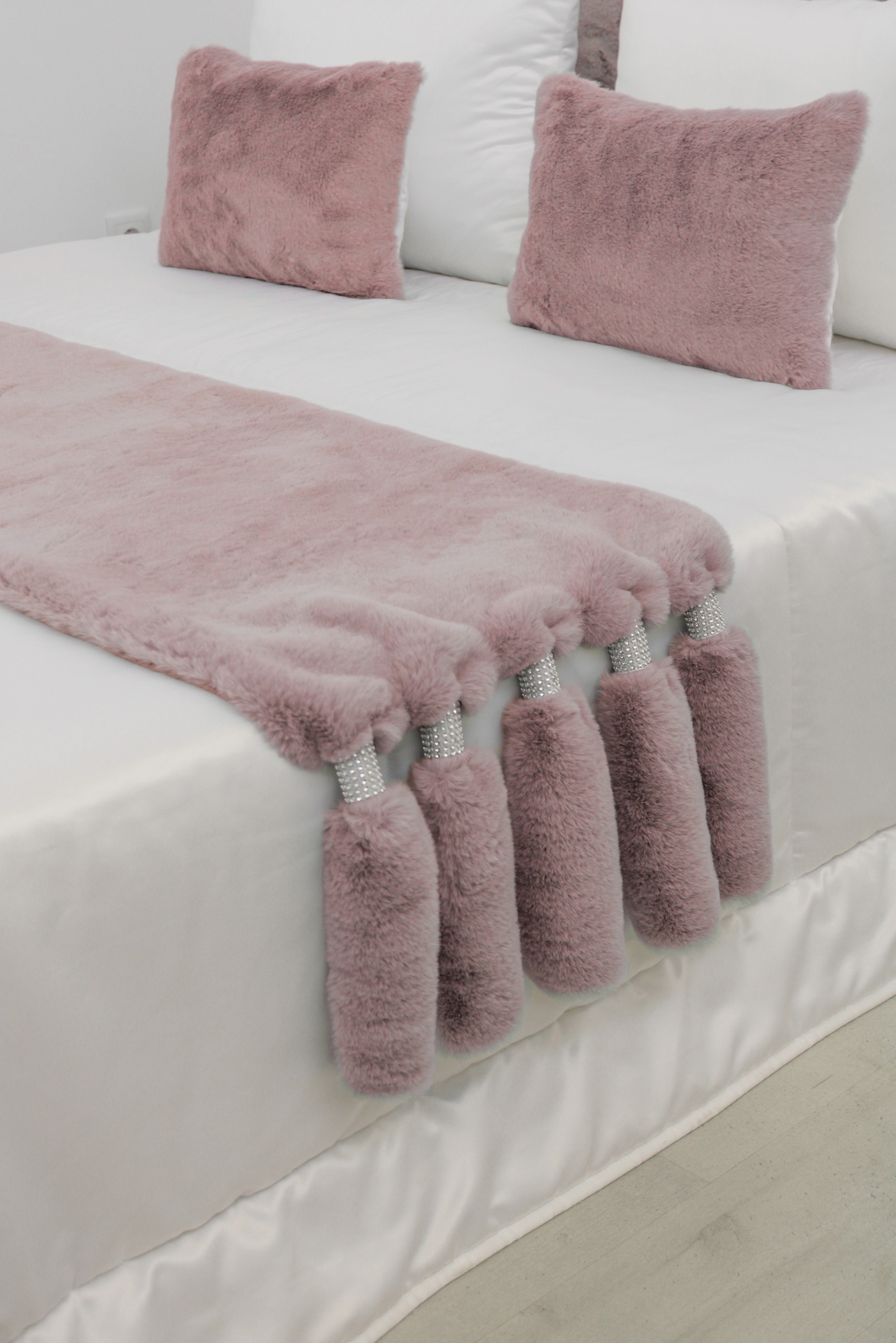 Cobertor e almofadas felpudas cor de rosa sobre cama branca