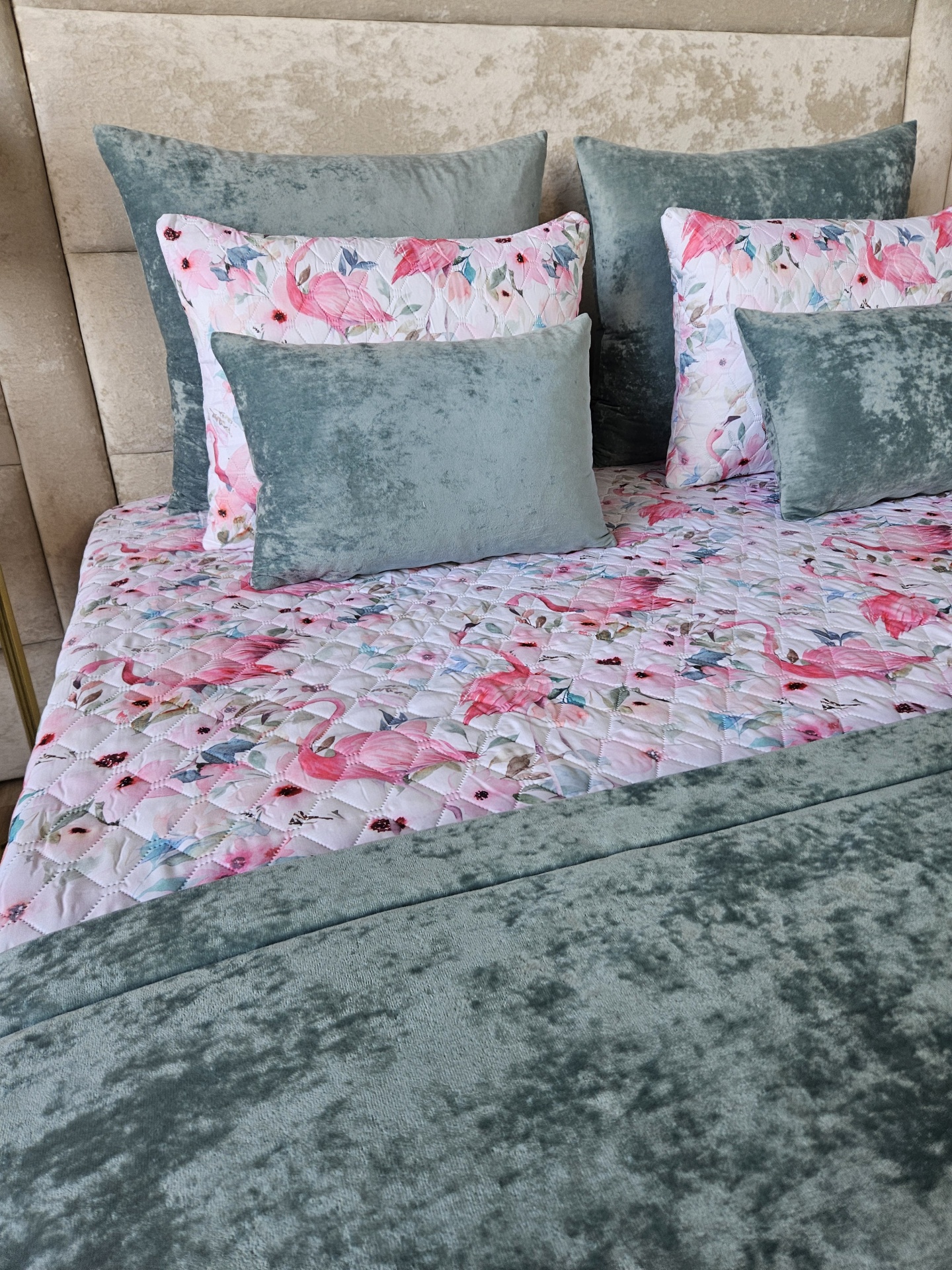 Cama com edredão floral e almofadas de veludo cinza