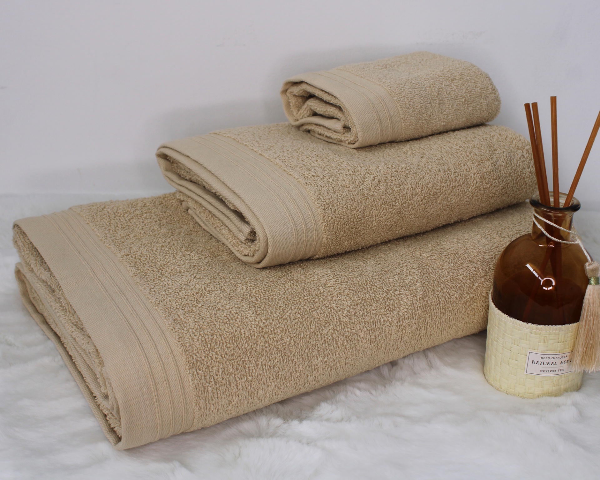 Três toalhas castanhas empilhadas e frasco com varetas aromáticas