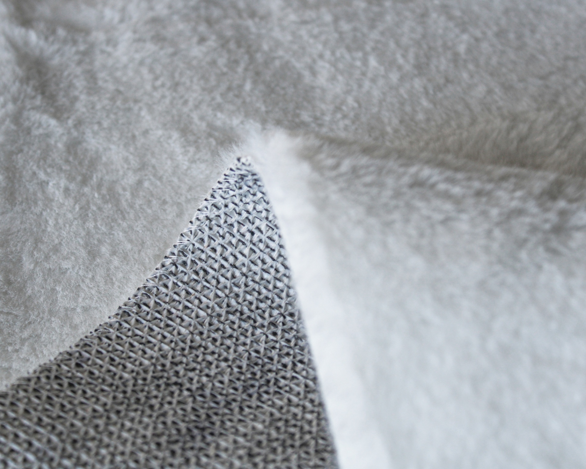 Tecido cinza com padrão entrelaçado e acabamento felpudo branco