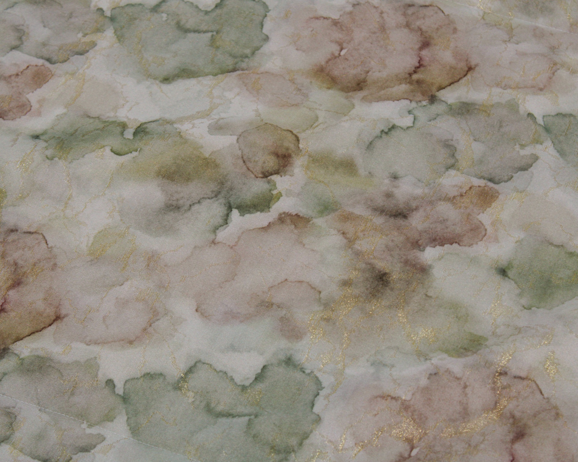Tecido com padrão aquarelado verde, castanho e bege com linhas douradas