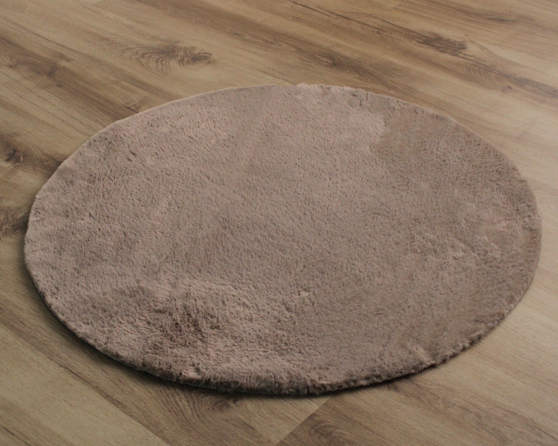 Tapete redondo castanho claro em chão de madeira