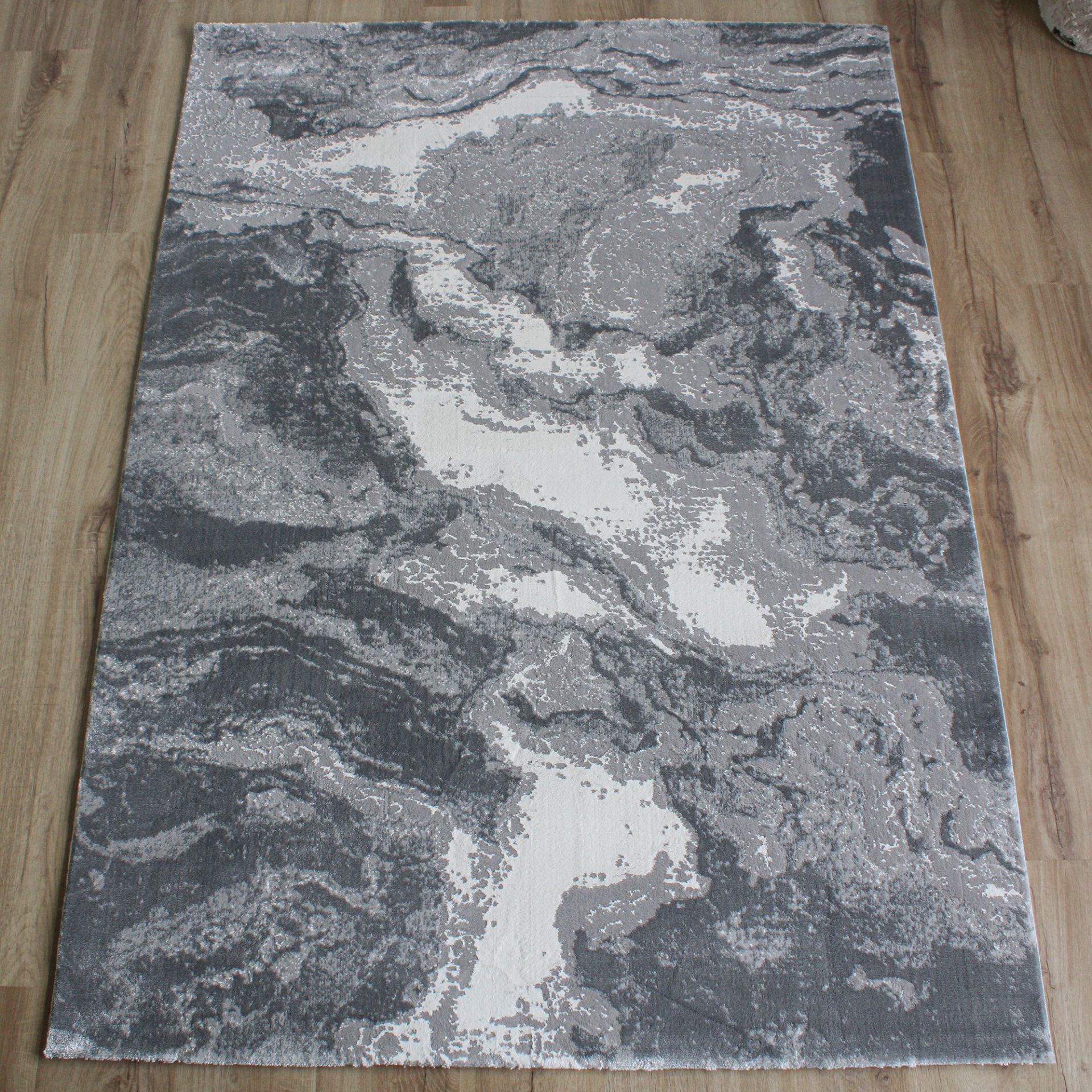 Tapete cinza com padrão abstrato sobre chão de madeira clara