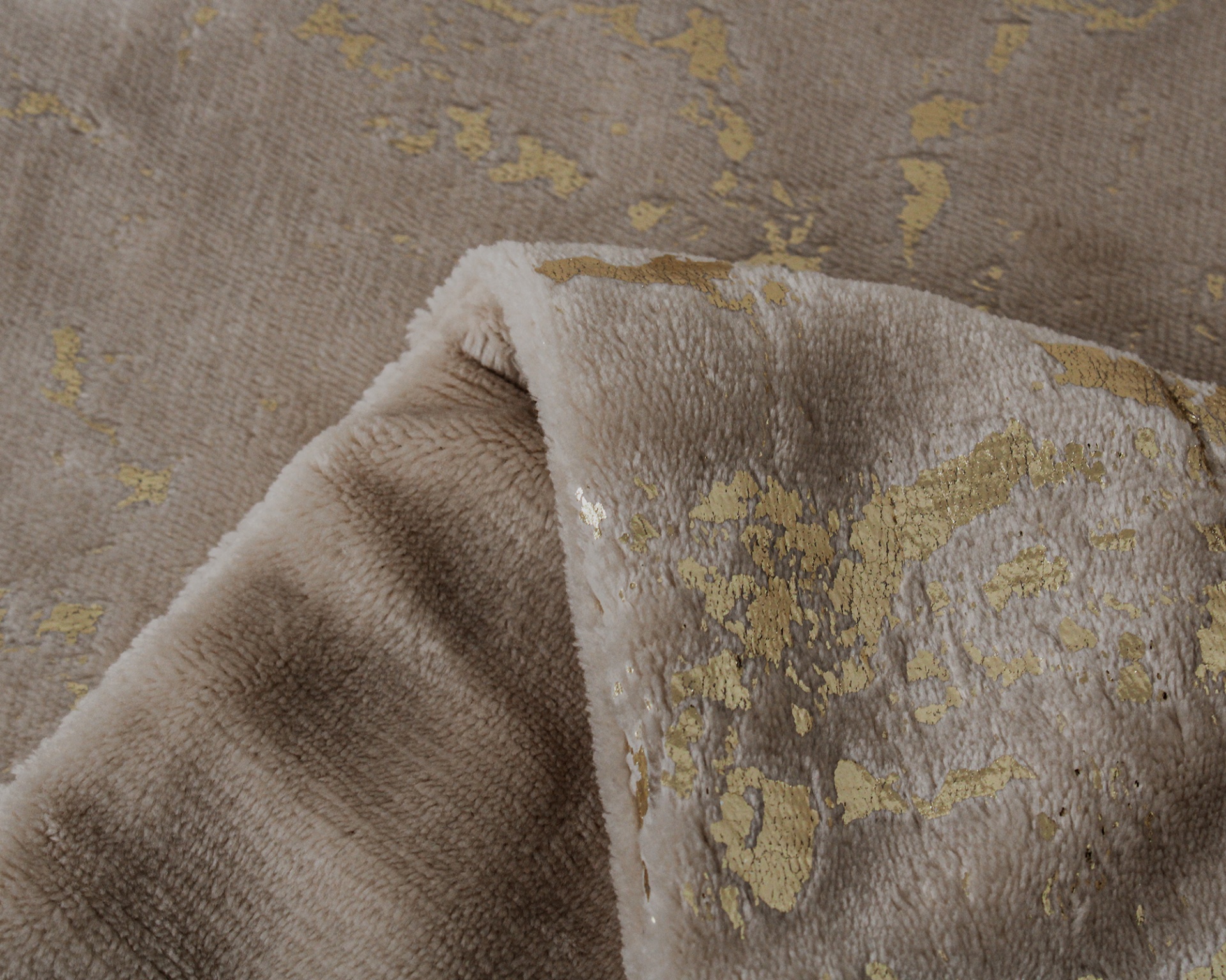 Tapete peludo bege com detalhes dourados e textura suave dobrado