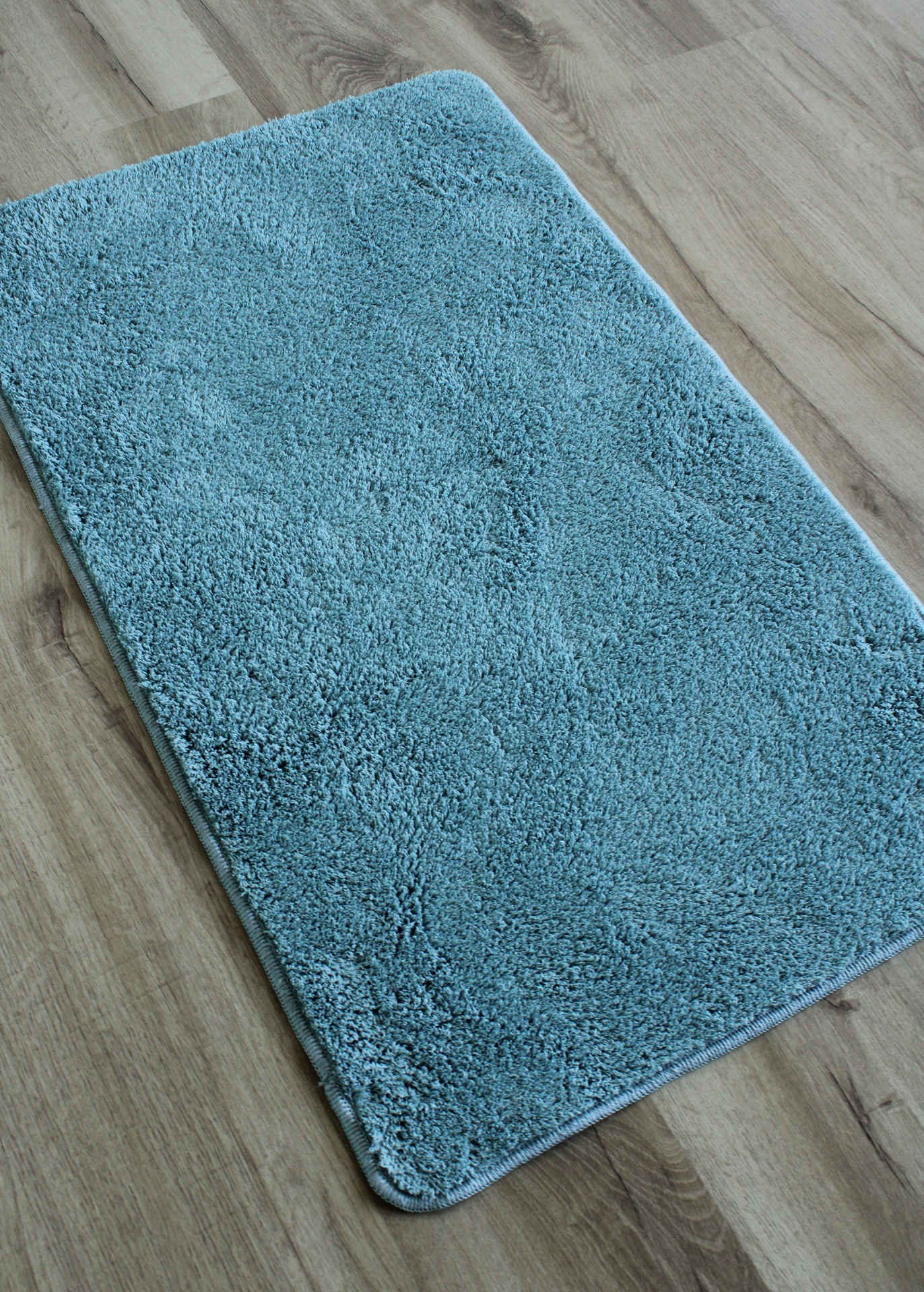 Tapete azul felpudo sobre chão de madeira clara
