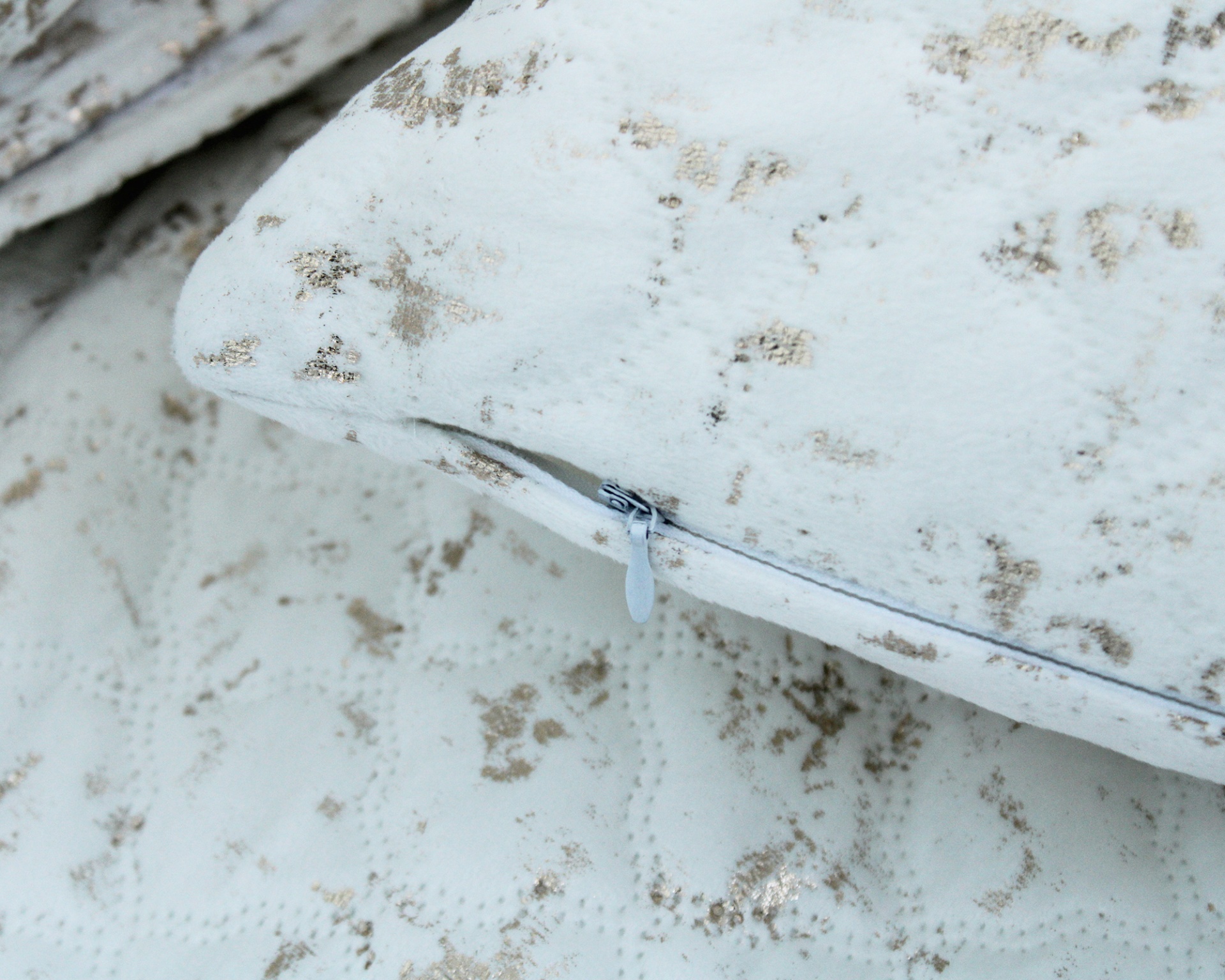 Travesseiro e cama branco com manchas douradas e padrão acolchoado