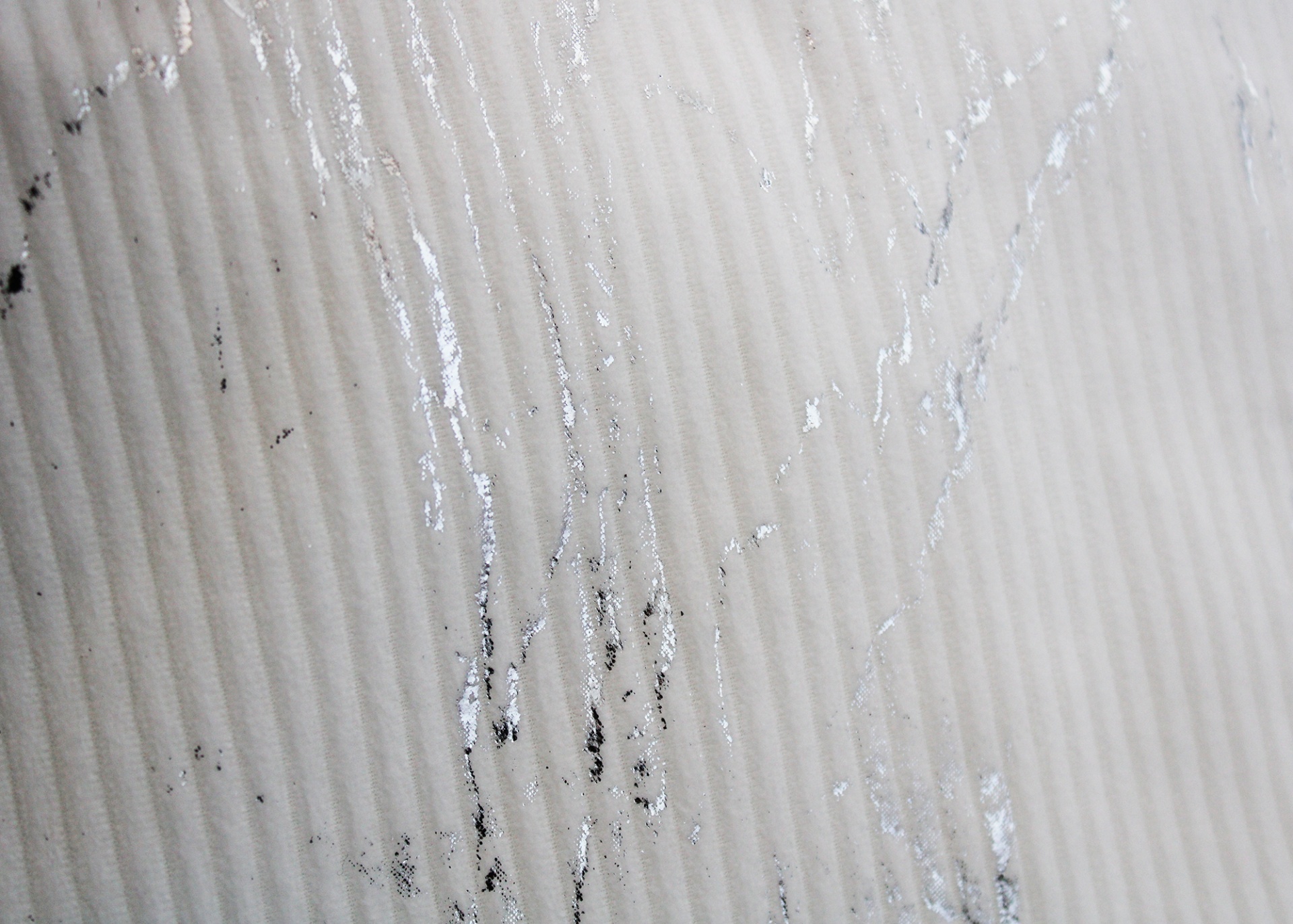 Superfície creme ripada com manchas pretas e textura brilhante