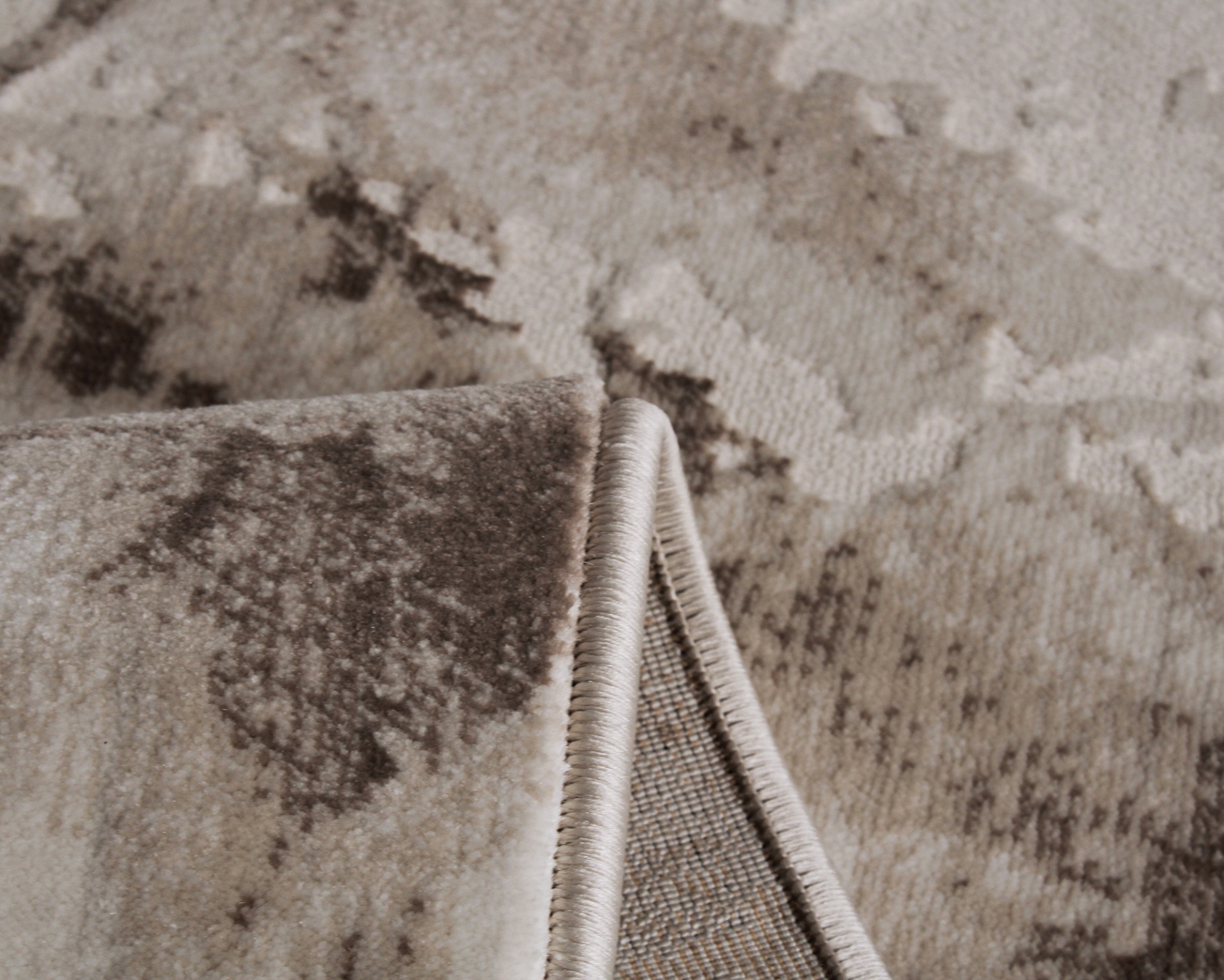 Tapete com padrão abstrato bege e castanho, textura felpuda, borda enrolada.