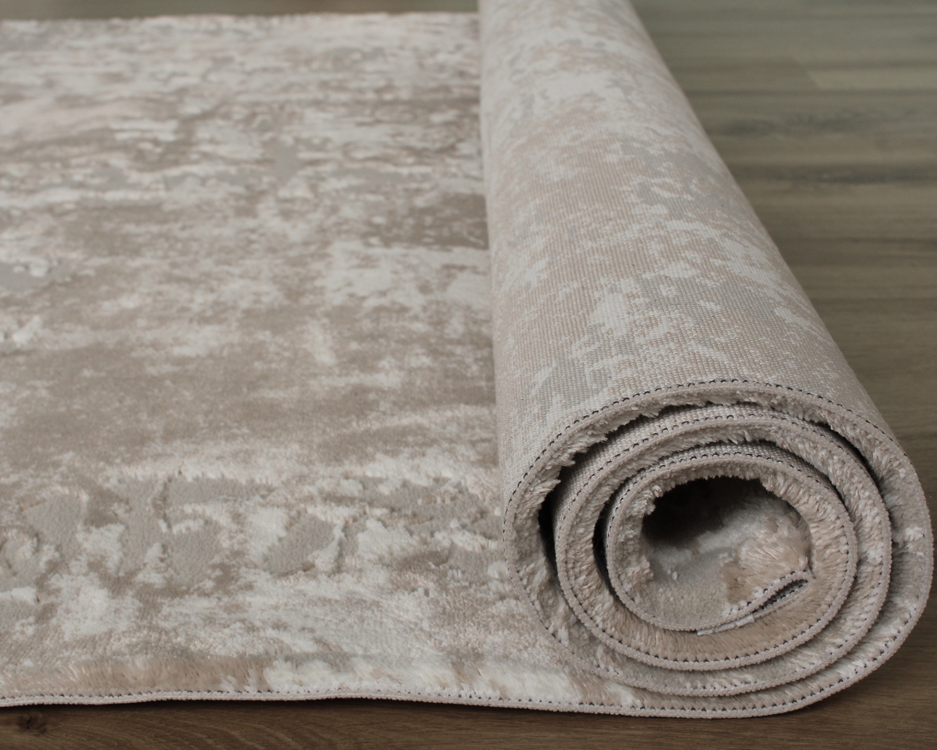 Tapete bege enrolado com padrão texturizado em chão de madeira clara