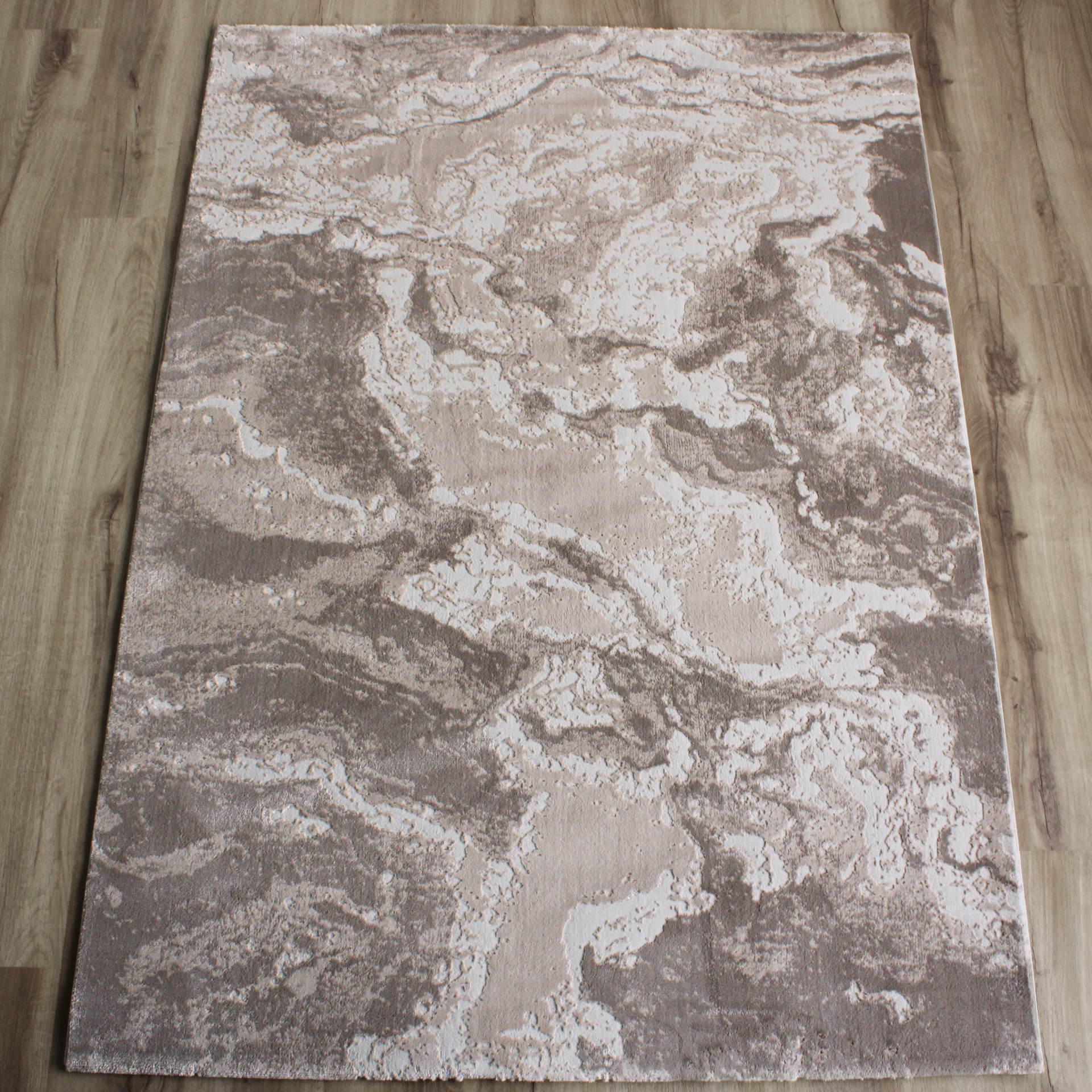 Tapete com padrão abstrato em creme e castanho sobre chão de madeira clara