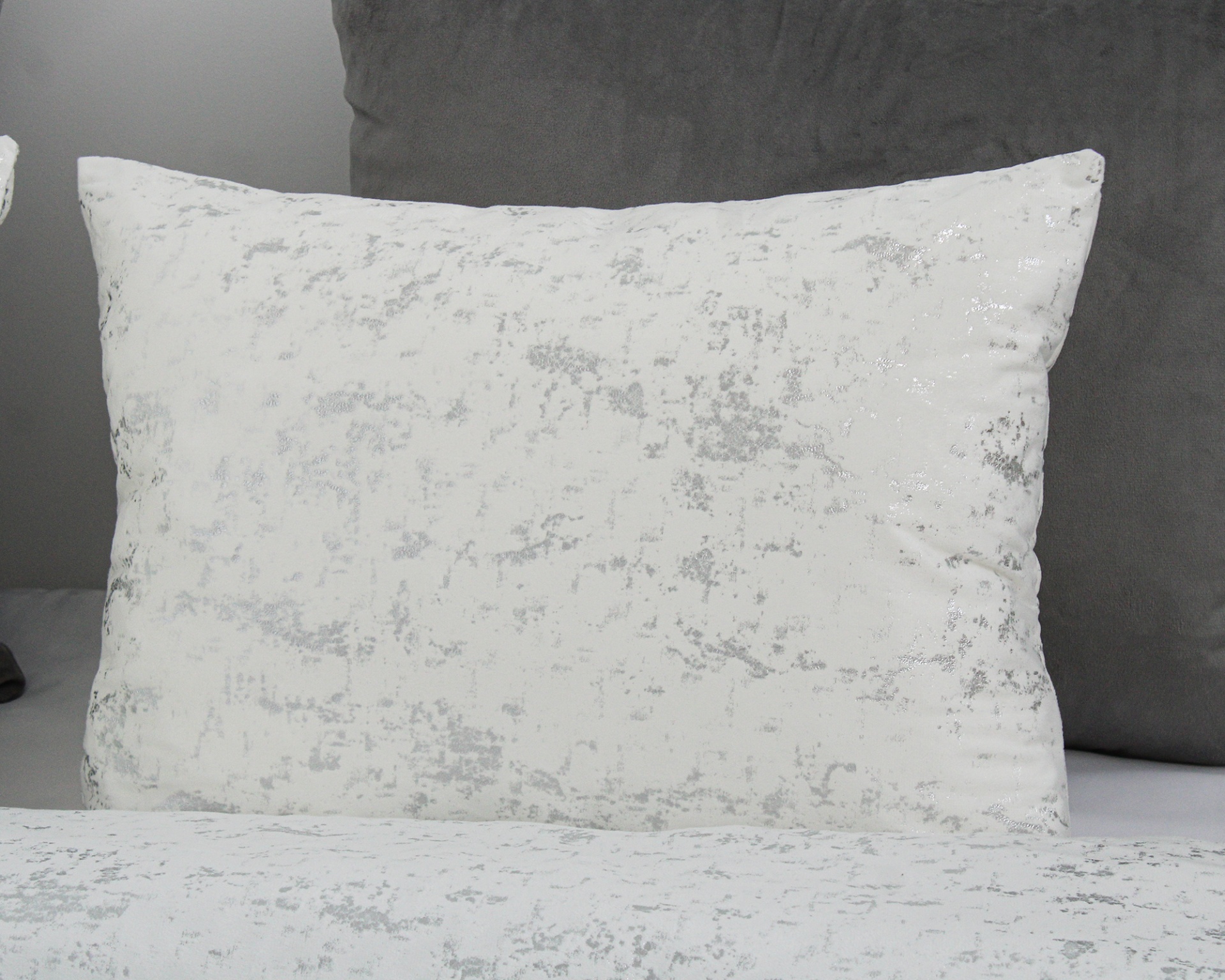 Travesseiro branco com padrão cinza prateado sobre cama