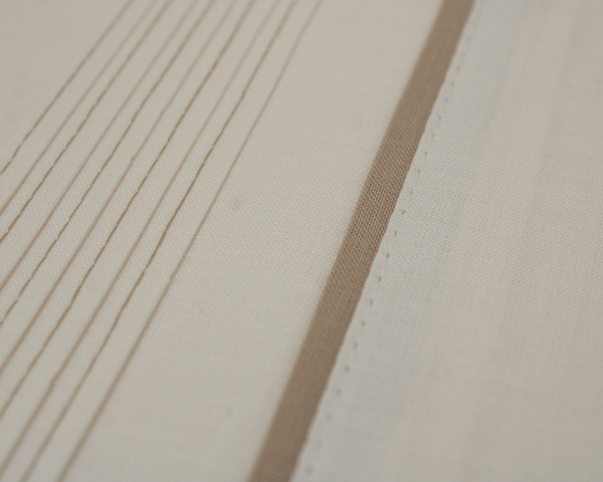 Tecido bege claro com riscas verticais castanhas e faixa castanha com costura