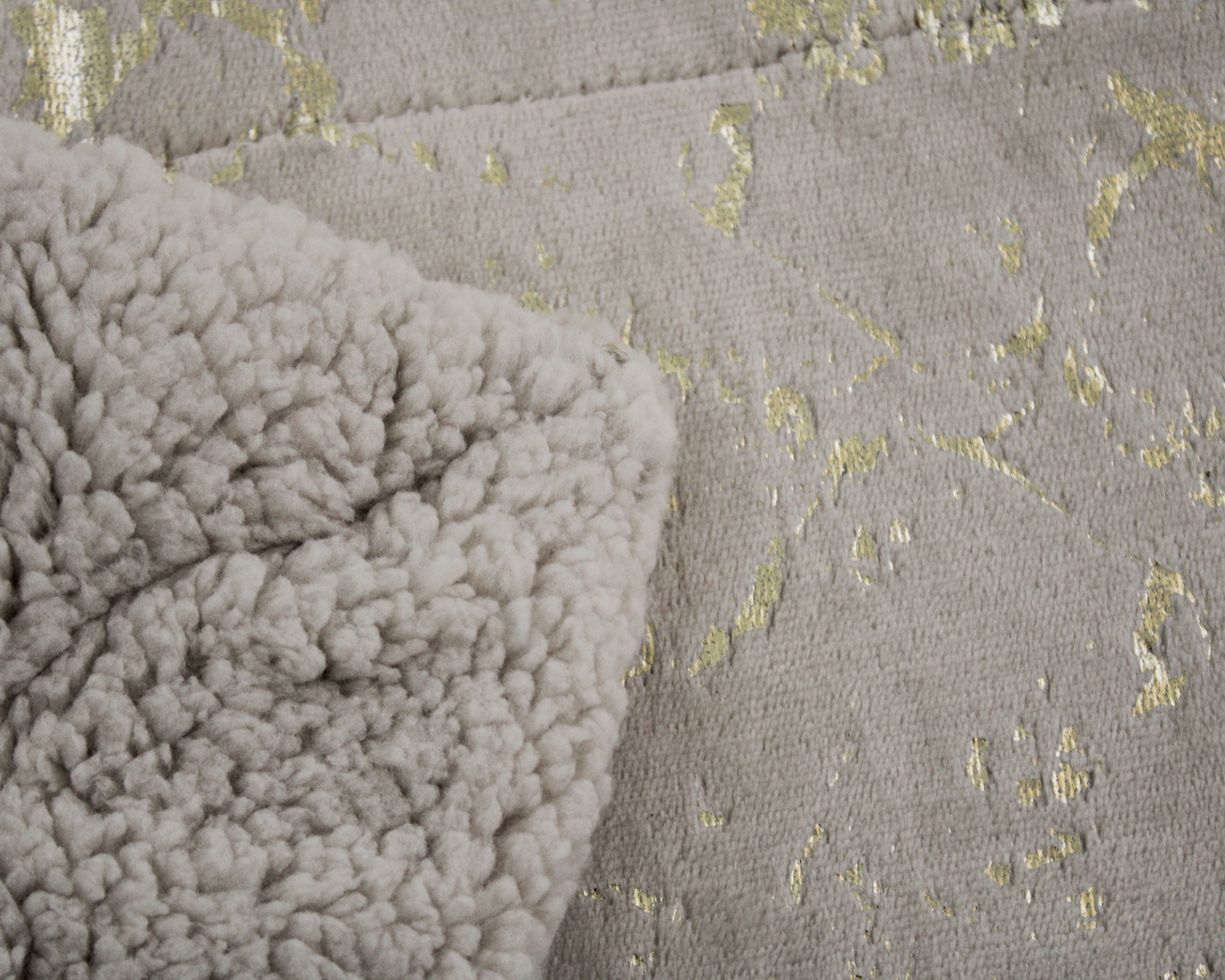 Pano cinzento felpudo com detalhes dourados em fundo cinzento têxtil