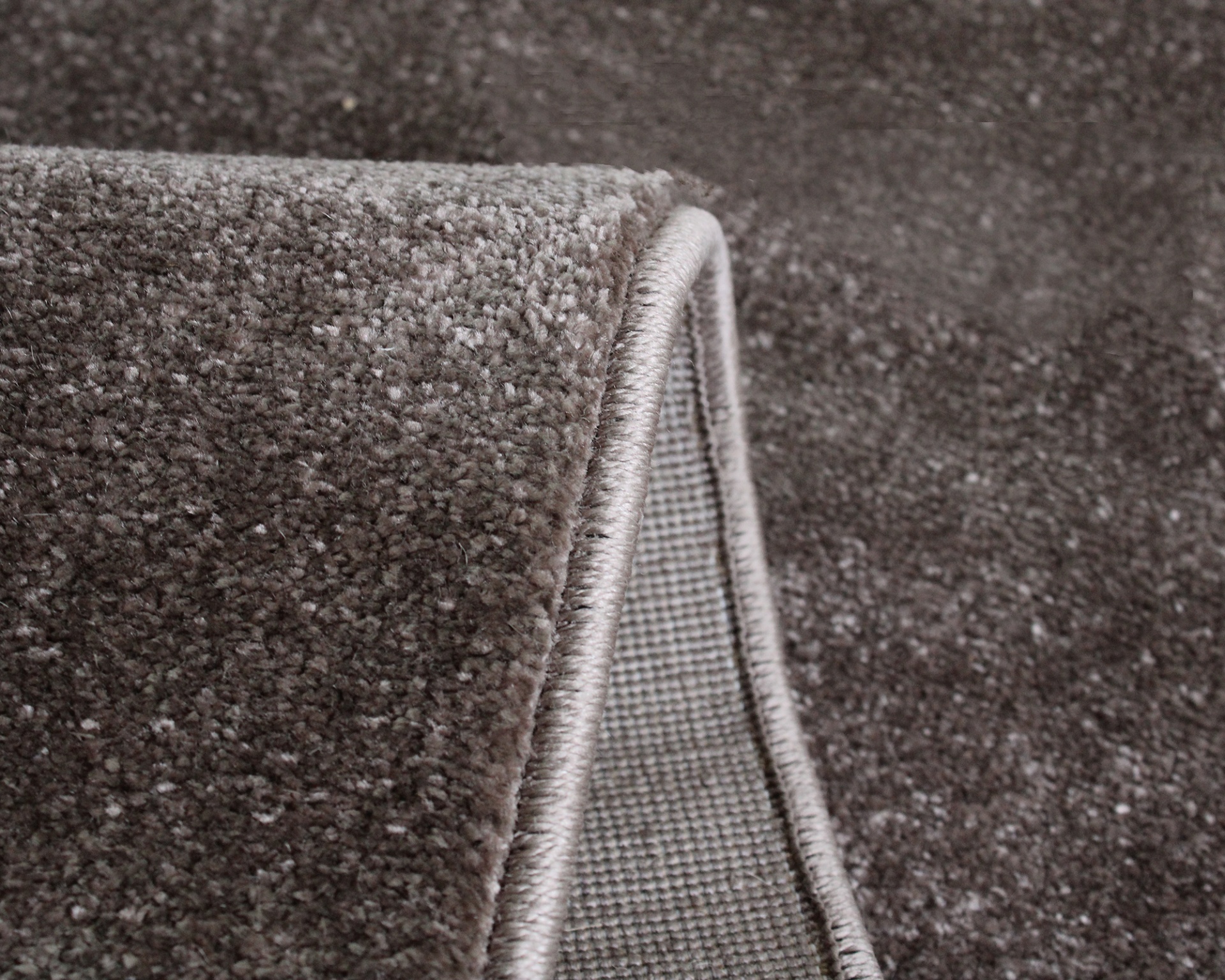 Tapete castanho texturizado com bordas costuradas e verso de trama mais rala