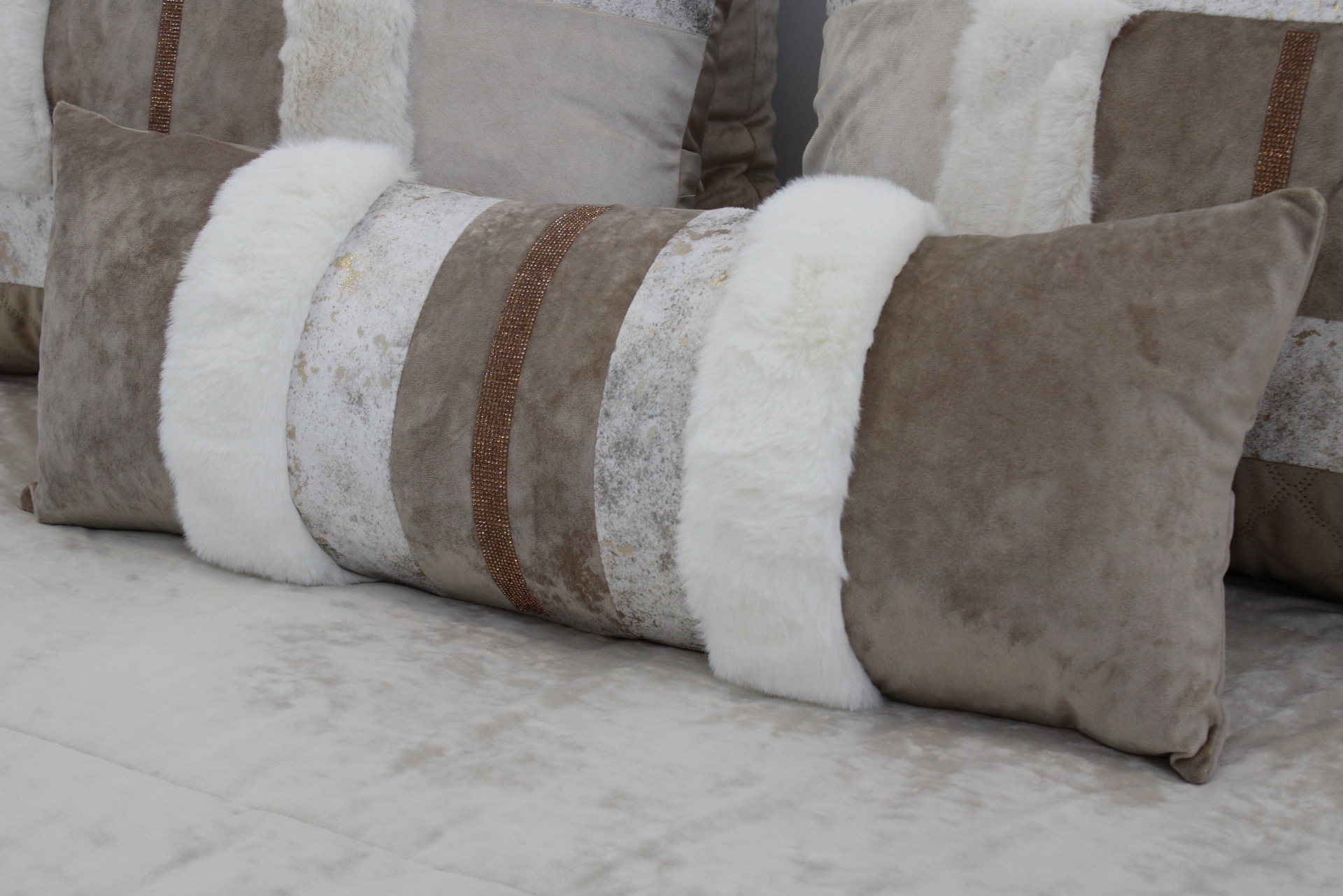 Almofada retangular com faixas brancas e castanhas sobre superfície clara