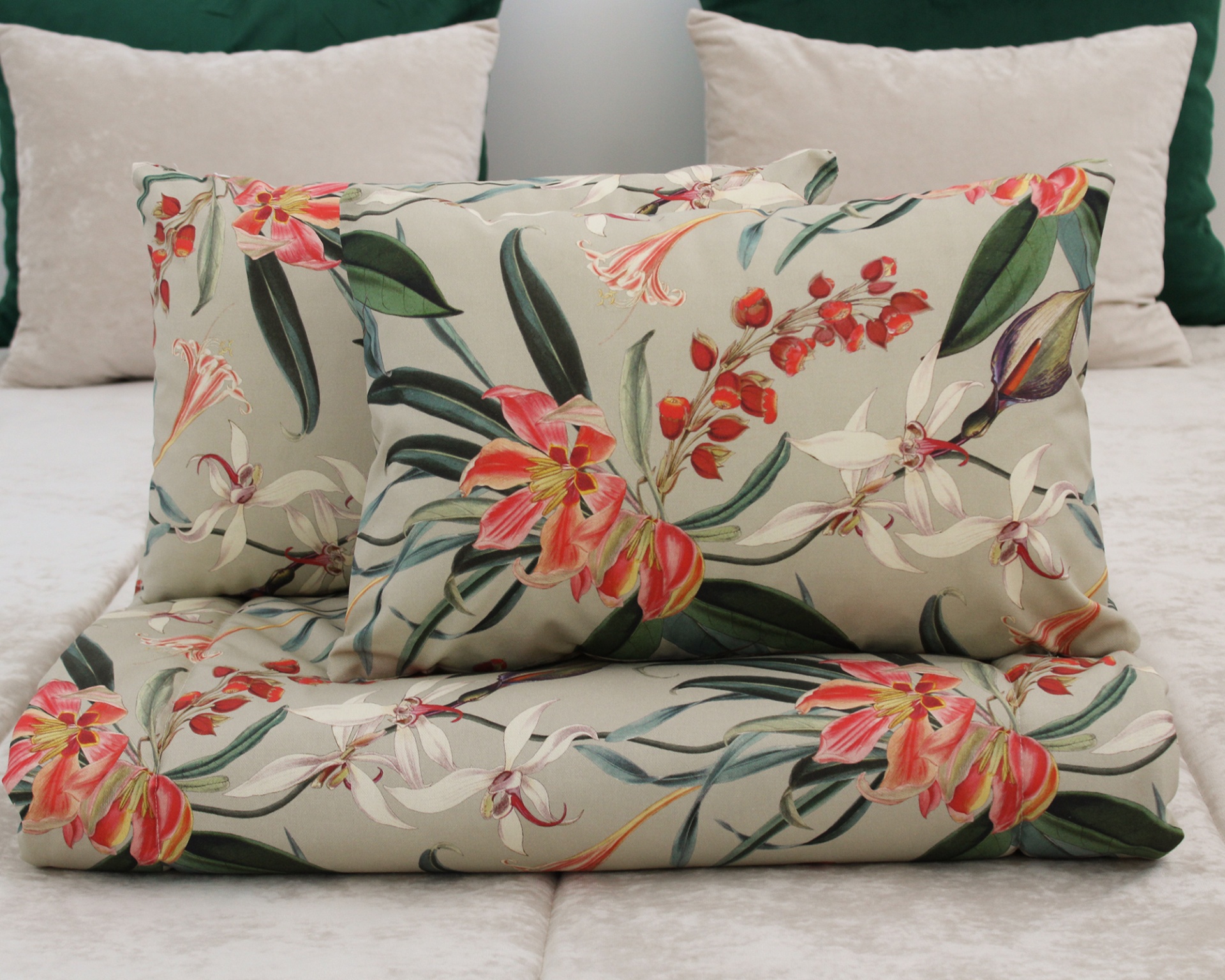Almofadas e manta com padrão floral colorido sobre cama com almofadas bege e verde