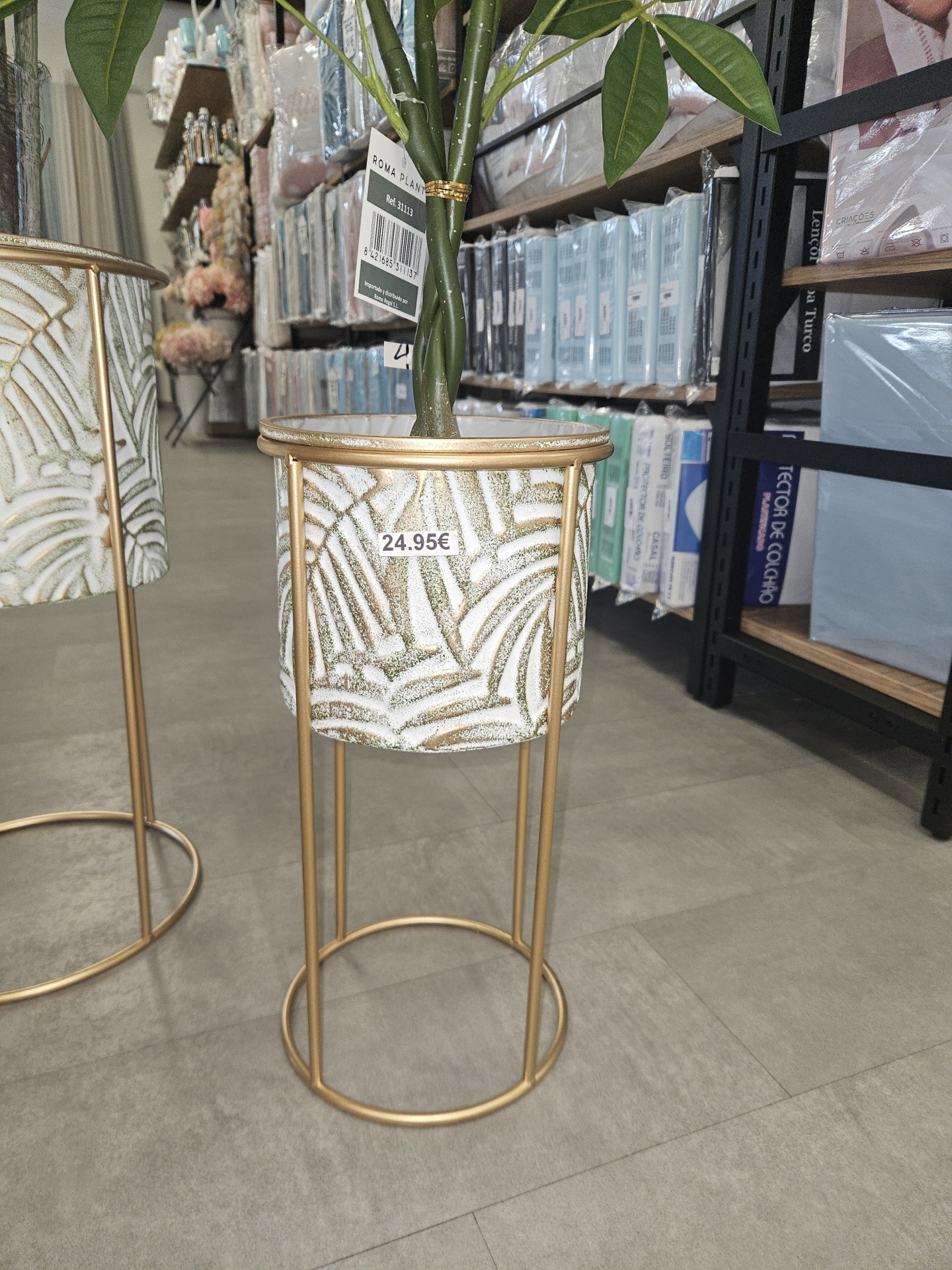 Vaso decorativo em suporte metálico dourado com planta artificial e etiqueta de preço 24.95€