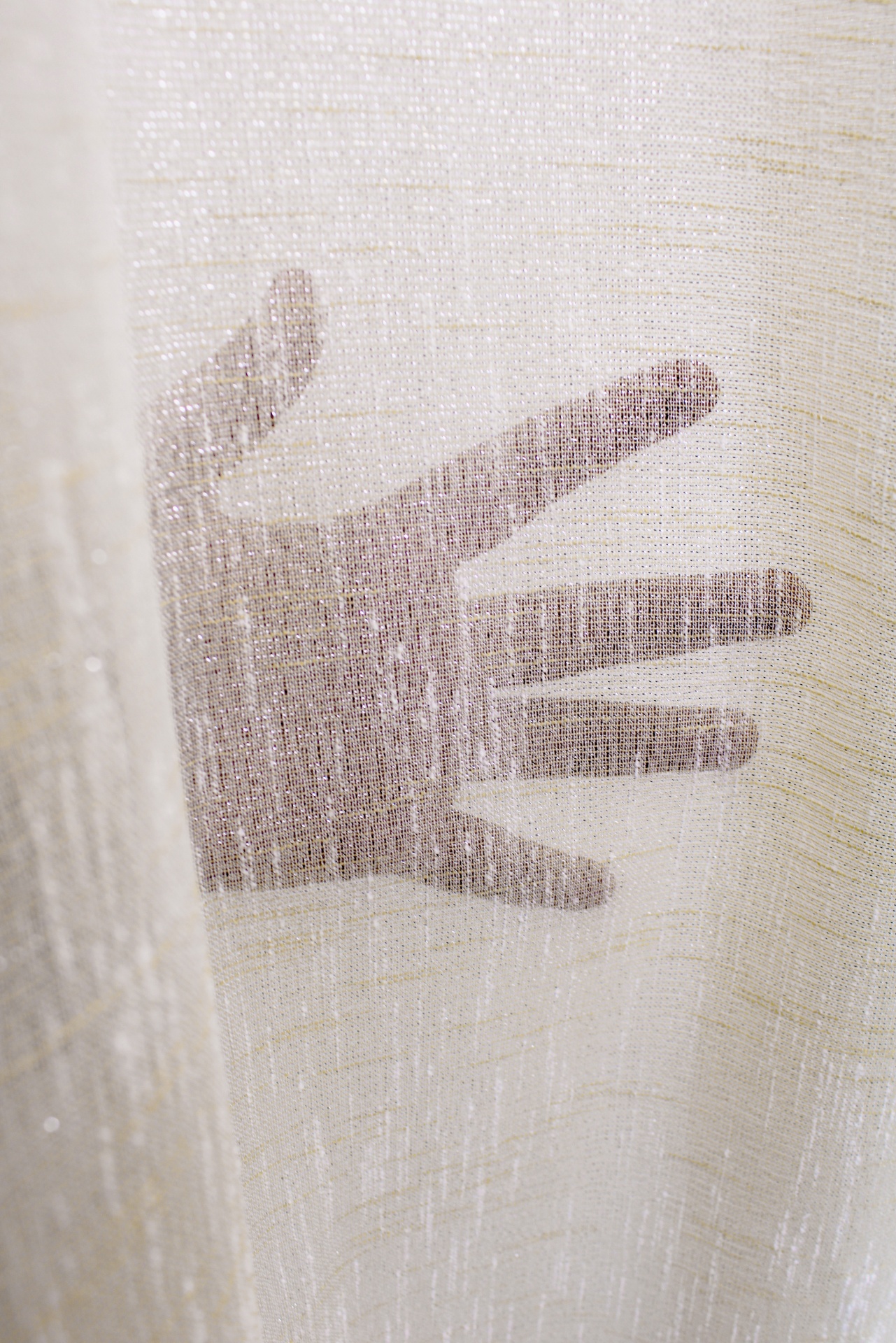 Mão por trás de tecido transparente branco com textura e brilho
