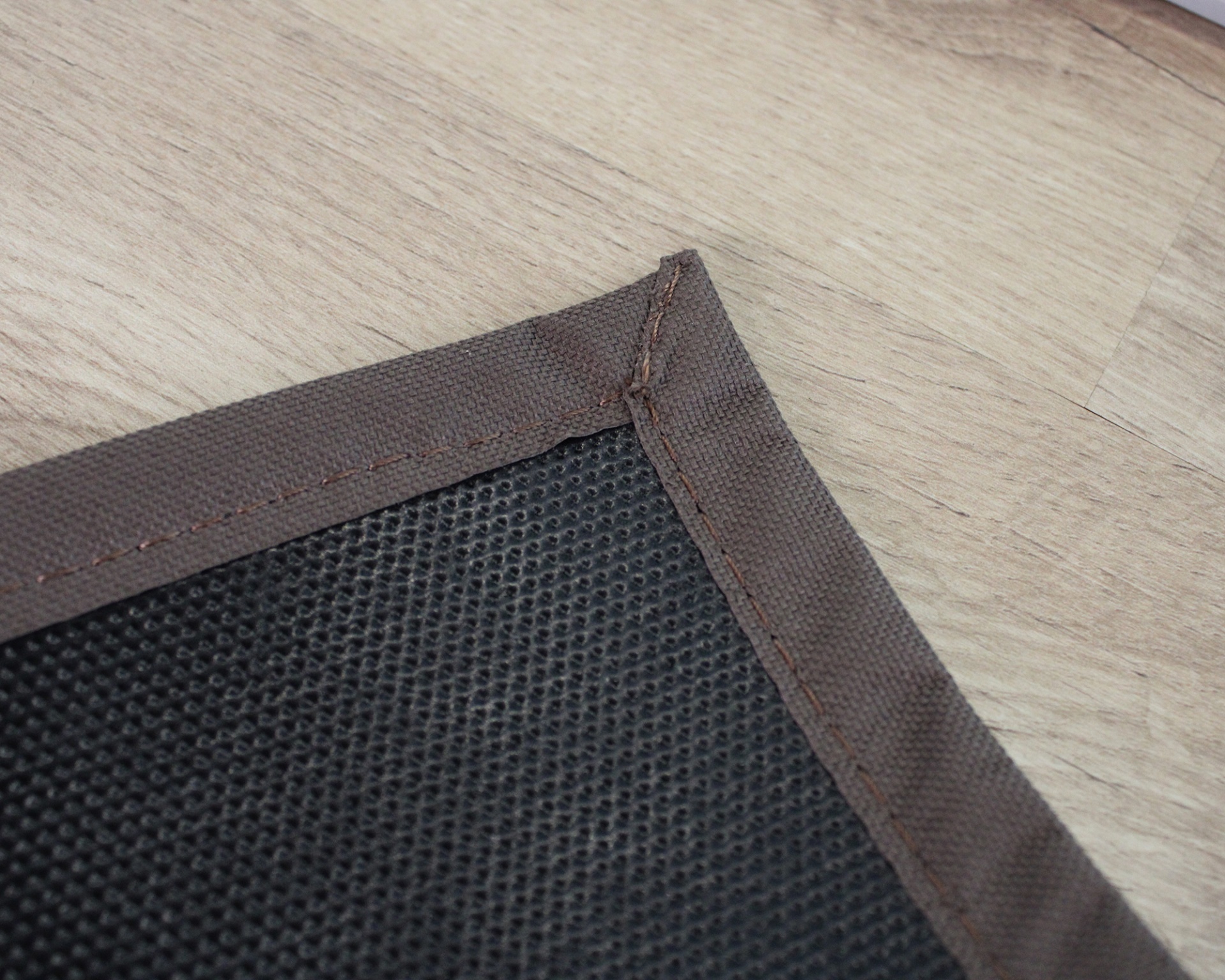 tapete ou almofada preta com borda castanha sobre chão de madeira