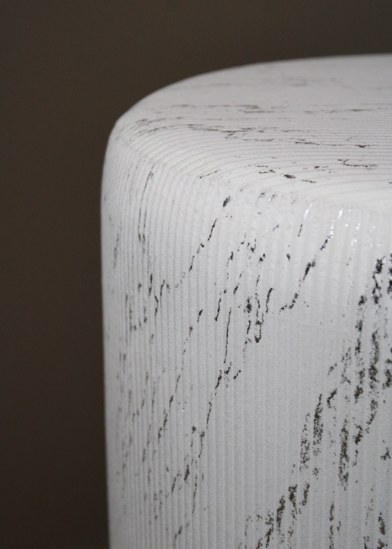 Detalhe de objeto cilíndrico branco com padrão cinzento e textura canelada