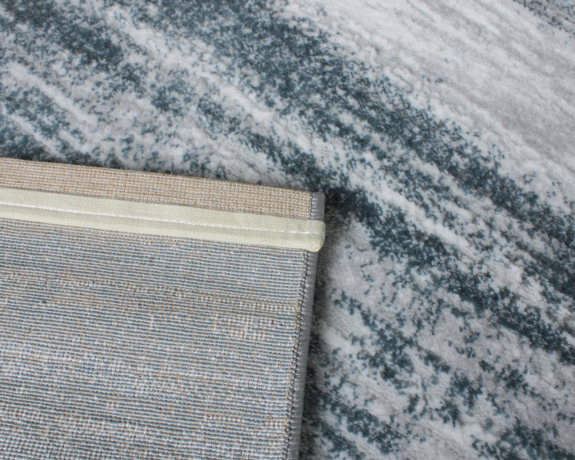 Tapetes sobrepostos com padrão abstrato cinza e listrado bege sobre piso claro