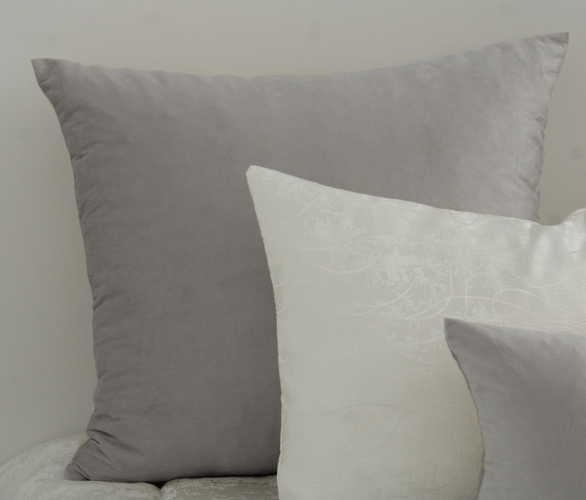 Três almofadas cinza e branca com padrão floral discreto