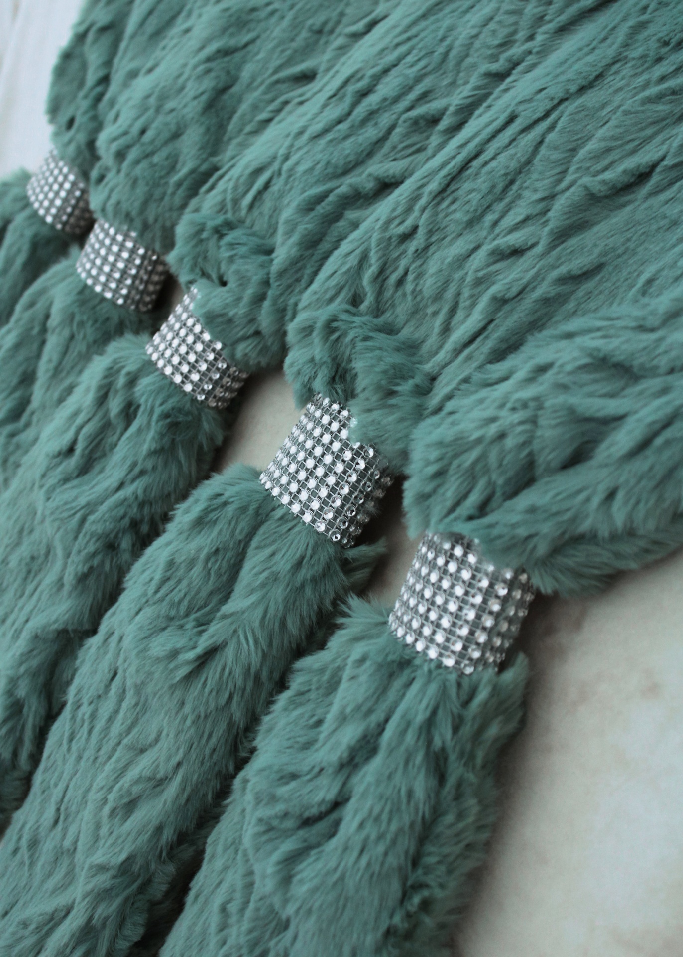 Tufos de tecido felpudo verde-azulado com argolas de strass prateadas