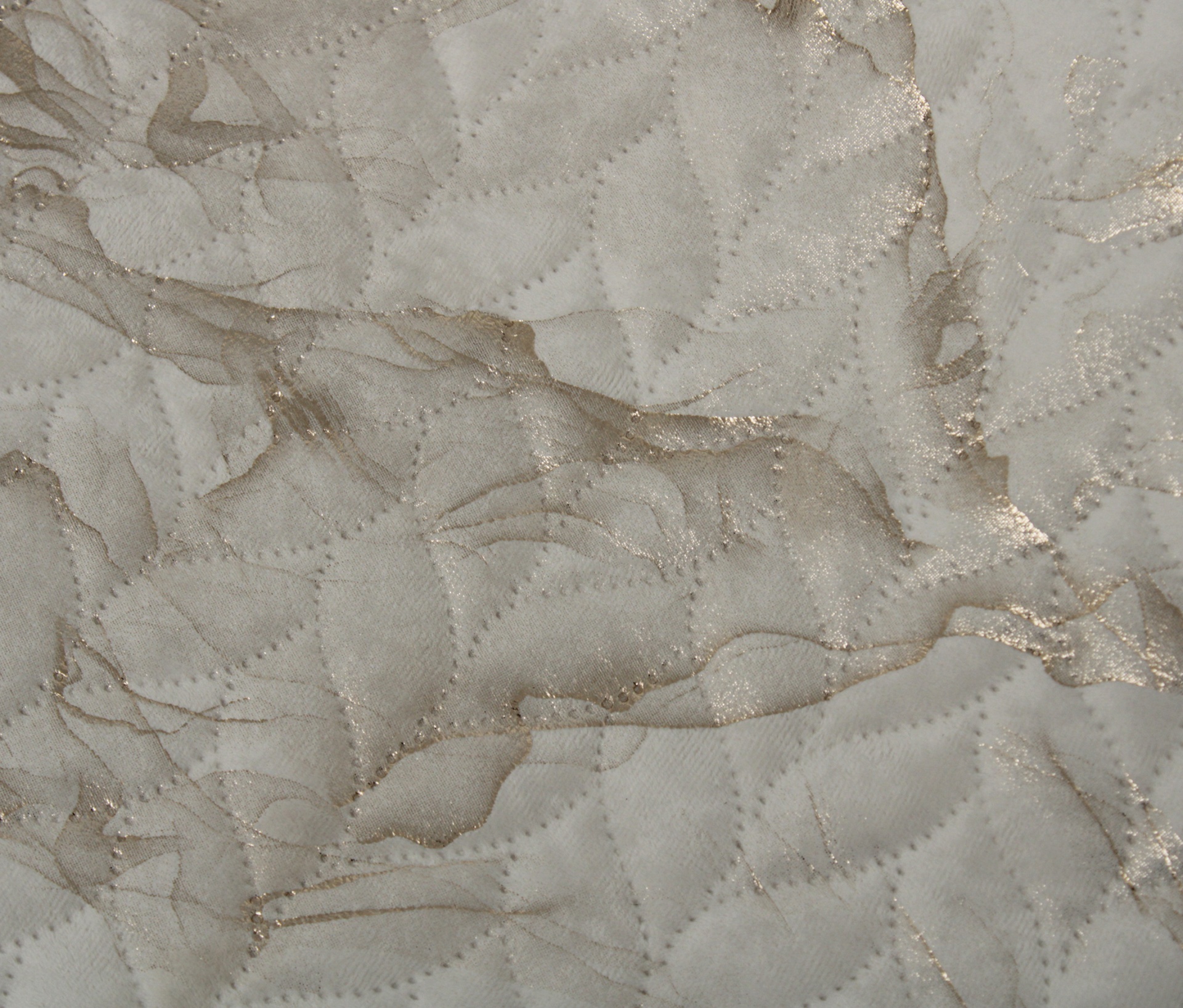 Pano acolchoado bege e dourado com padrão de costura