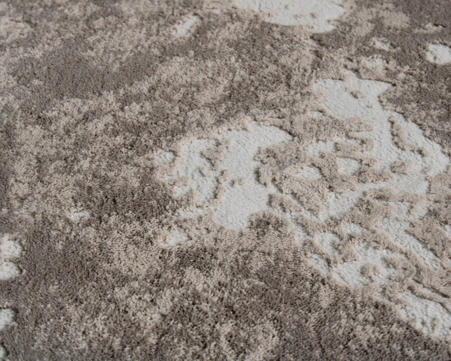 Tapete felpudo cinza bege com padrão floral e textura aveludada.