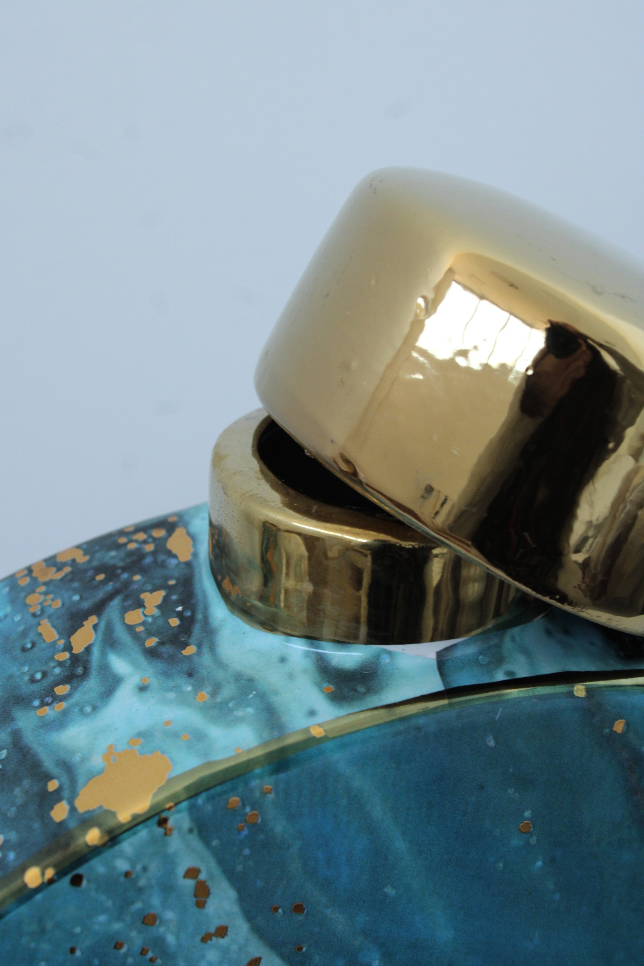 Garrafa com tampa dourada e corpo azul marmoreado com detalhes dourados