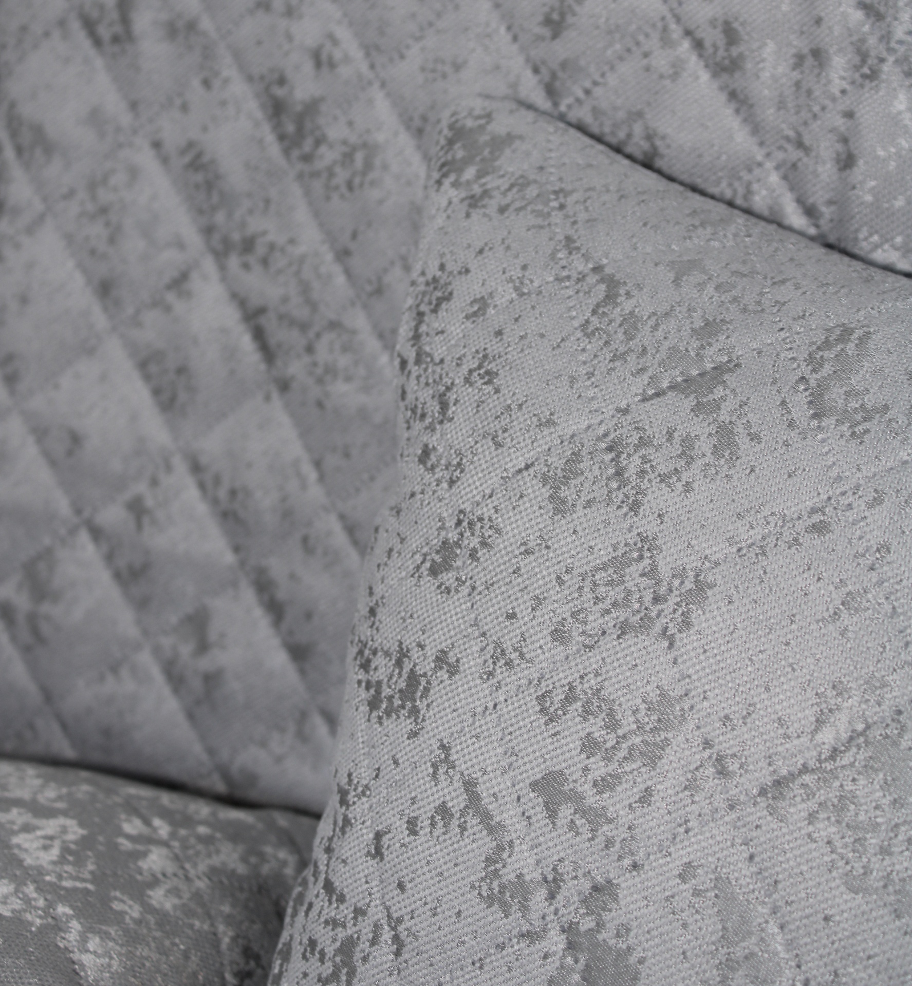 Almofada e sofá cinzentos com padrão abstrato e textura suave