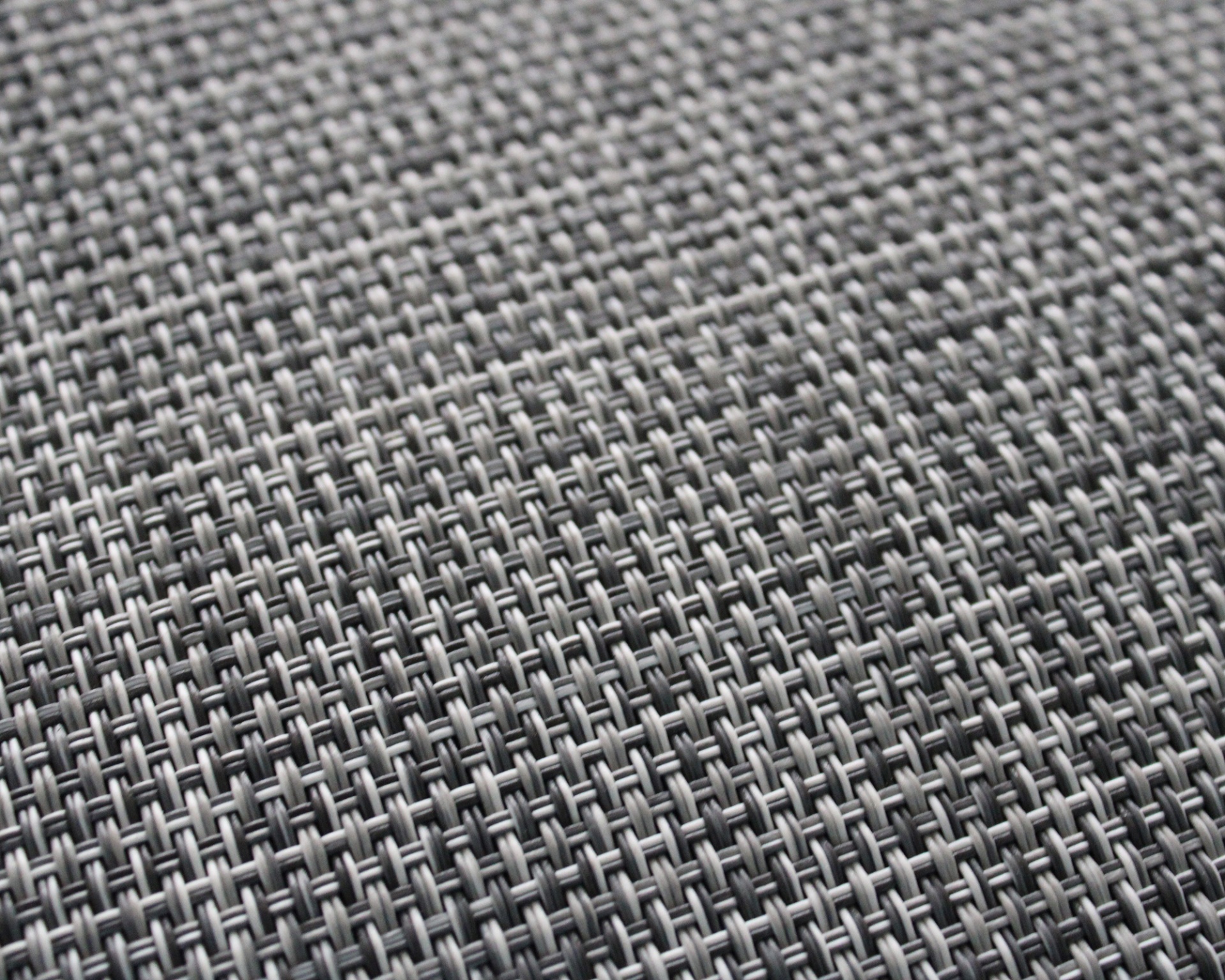 Tecido cinzento com padrão entrelaçado e textura regular.