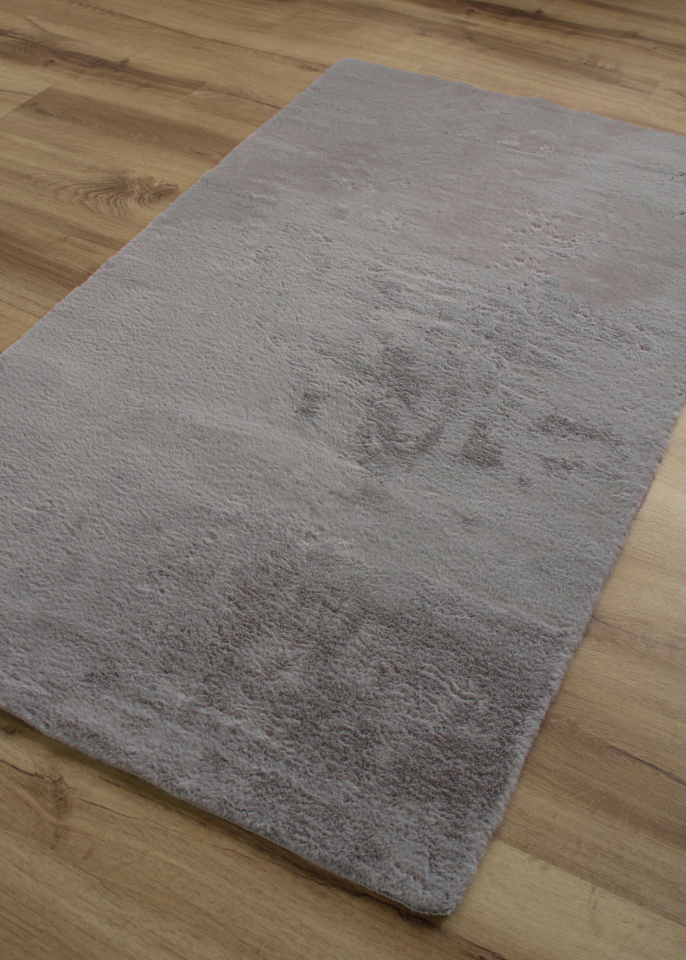 Tapete cinzento claro macio sobre chão de madeira