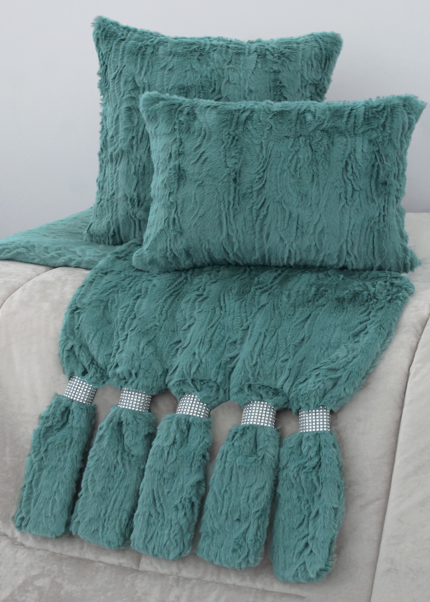 Almofadas e manta felpudas azul esverdeado com pompons decorativos e faixas brilhantes