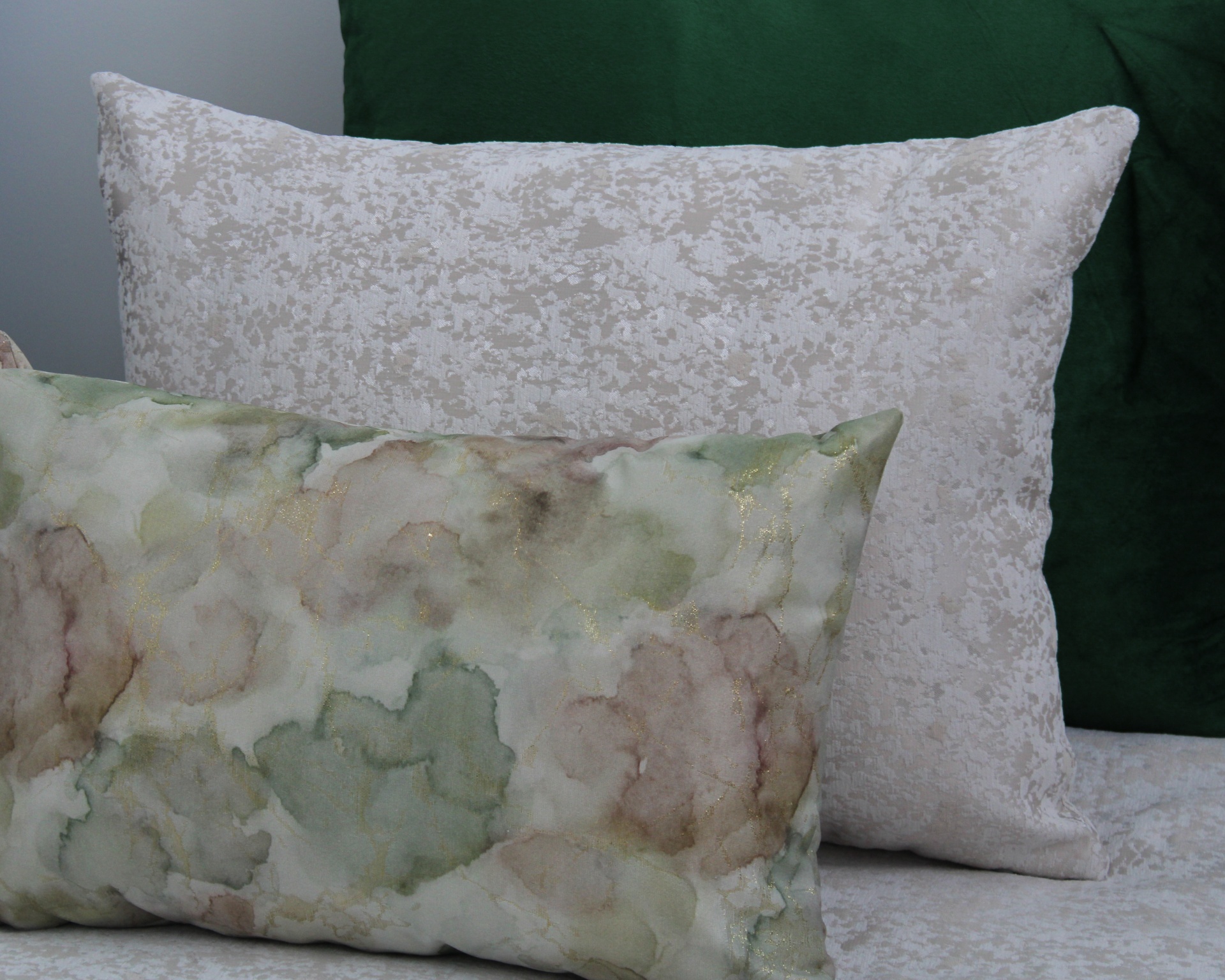 Conjunto de almofadas com padrão aquarela, textura floral e cor verde sólida.