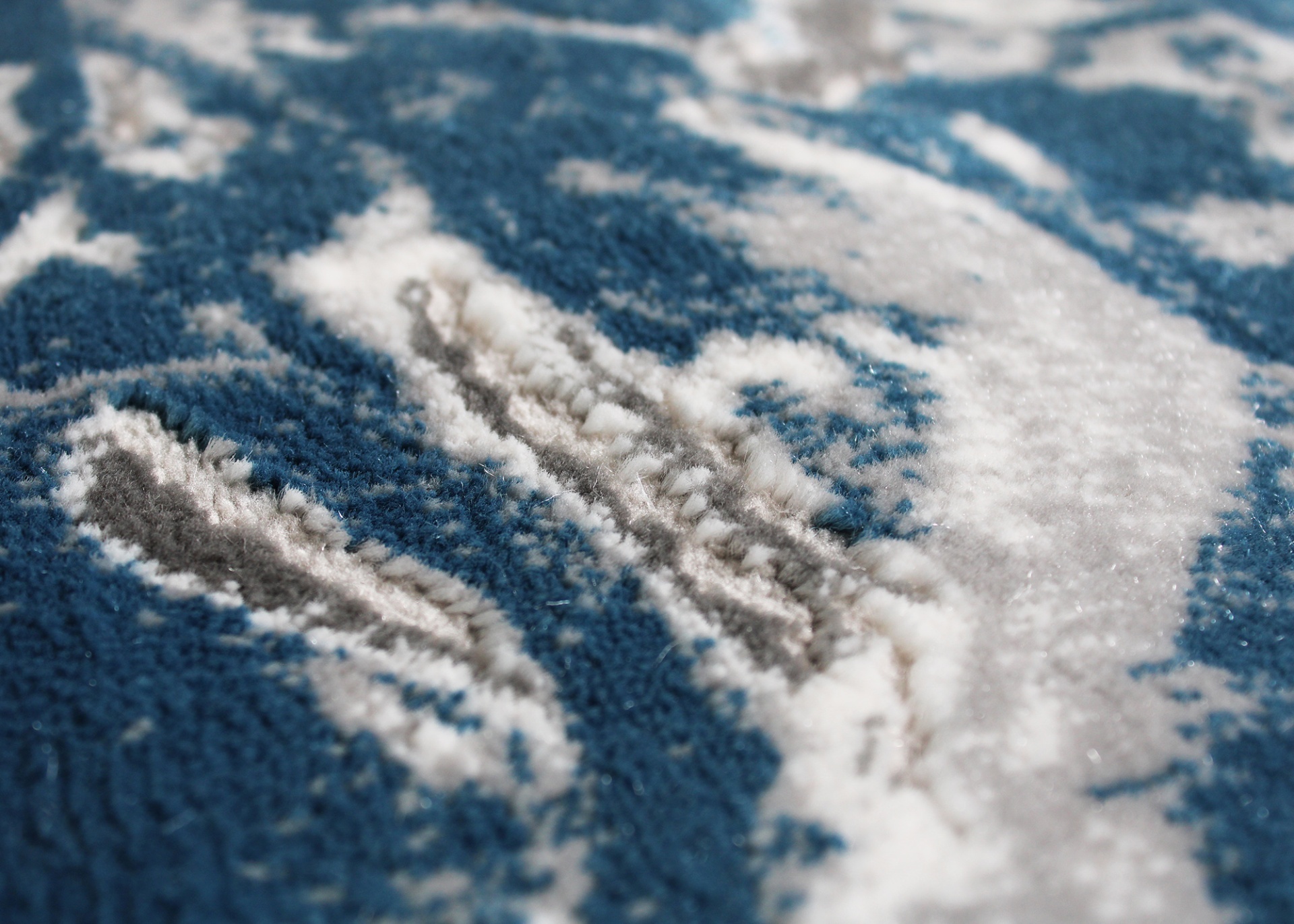 Textura detalhada de tapete azul com padrões brancos e cinza
