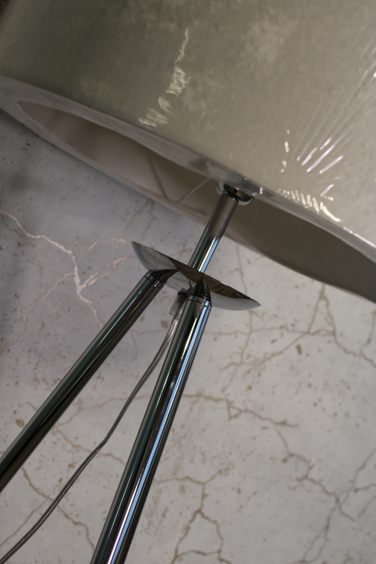 Lâmpada de pé com cúpula bege e estrutura metálica cromada em chão de mármore bege