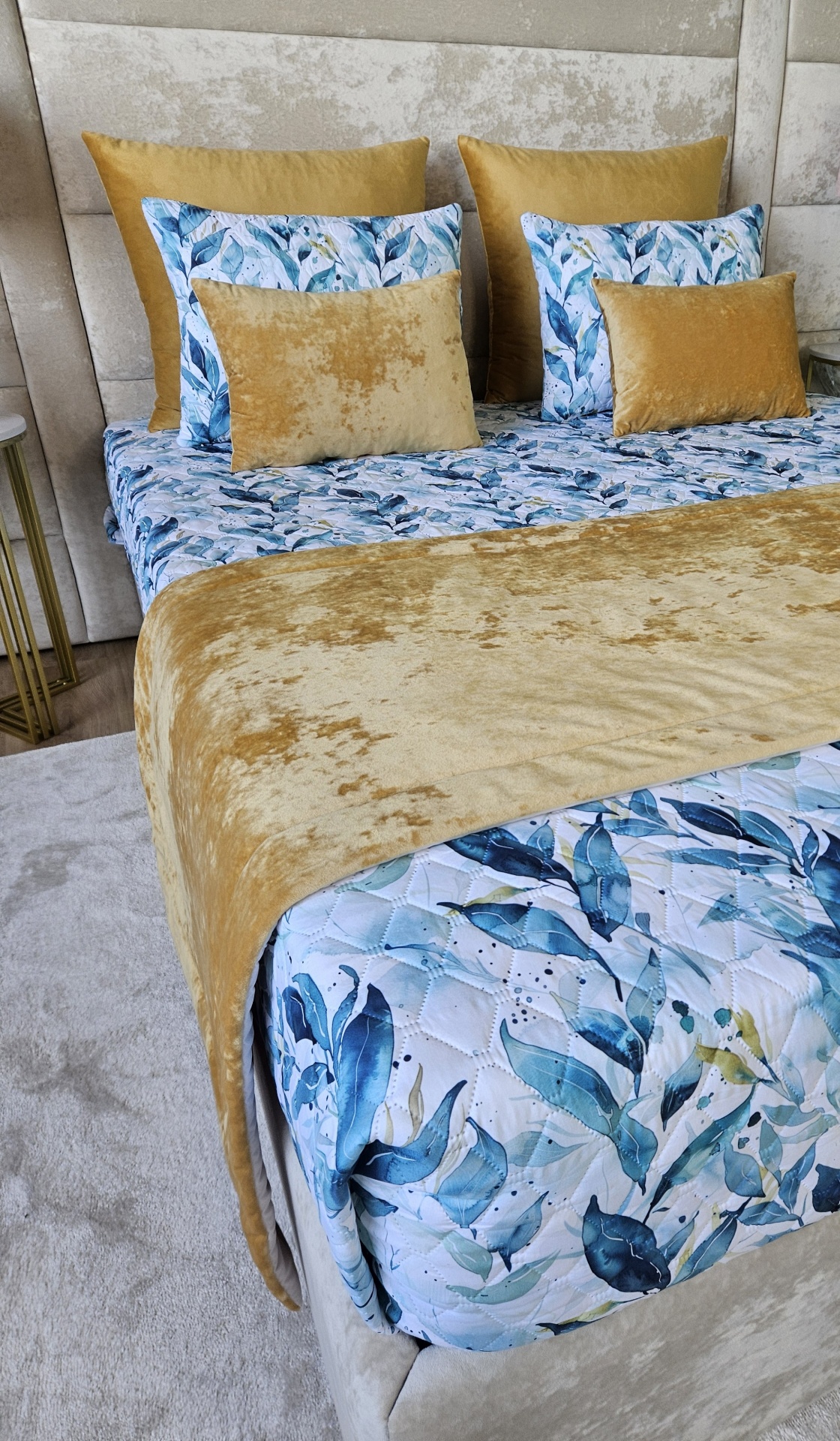 Cama com colcha e almofadas decorativas em tons azul, verde e amarelo mostarda