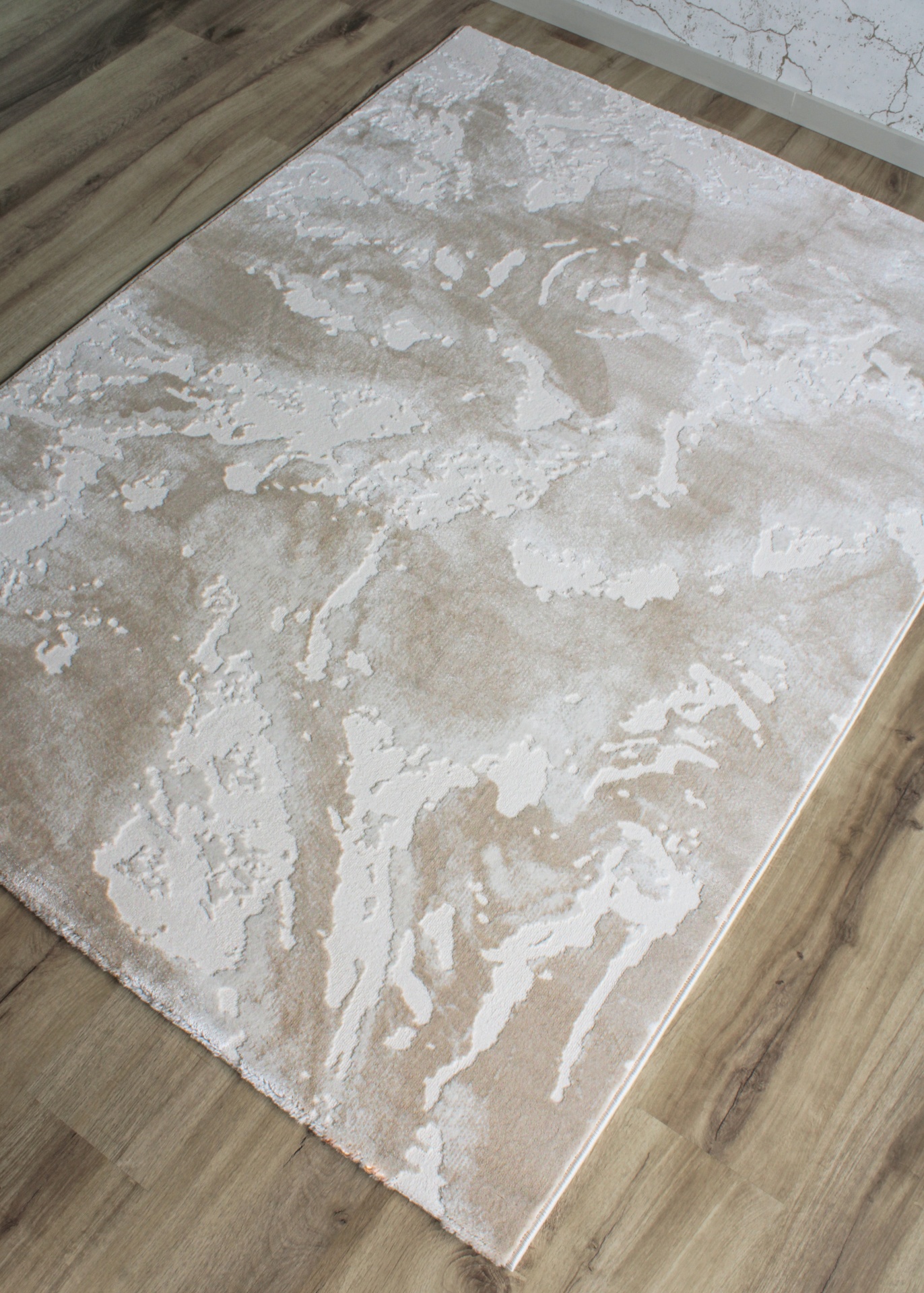 Tapete beige e creme com padrão abstrato sobre chão de madeira