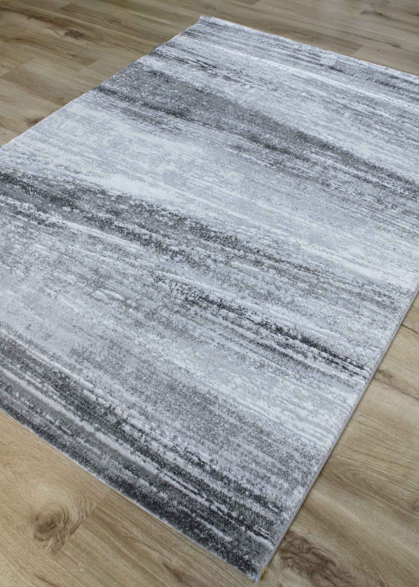 Tapete cinza abstrato sobre chão de madeira clara