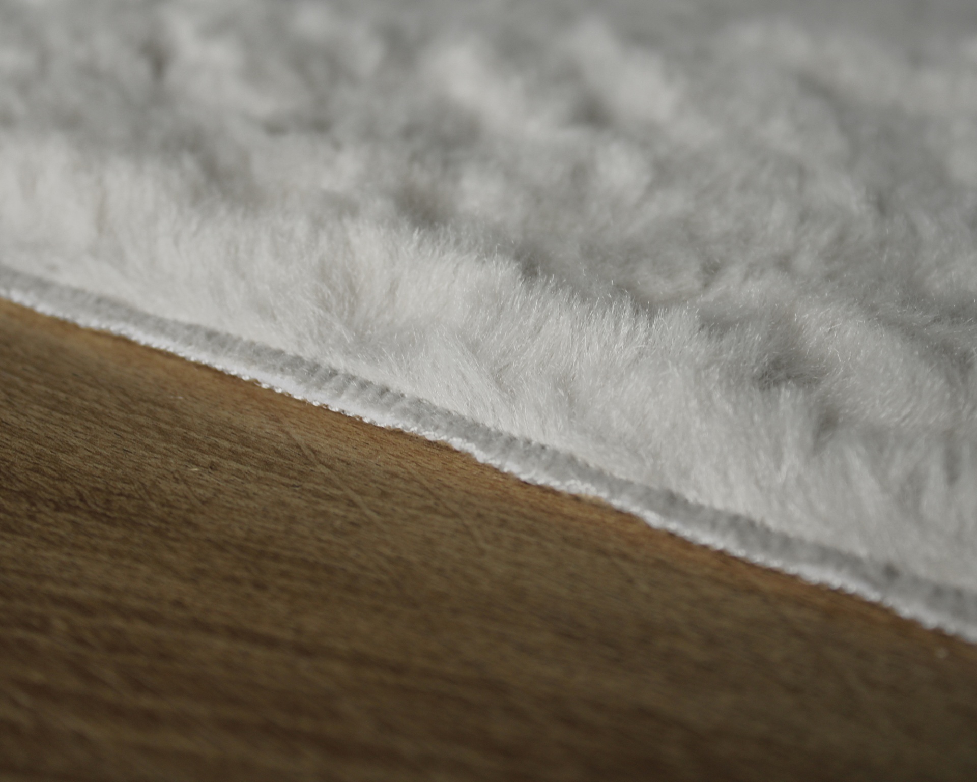 Tapete cinza claro felpudo sobre chão de madeira