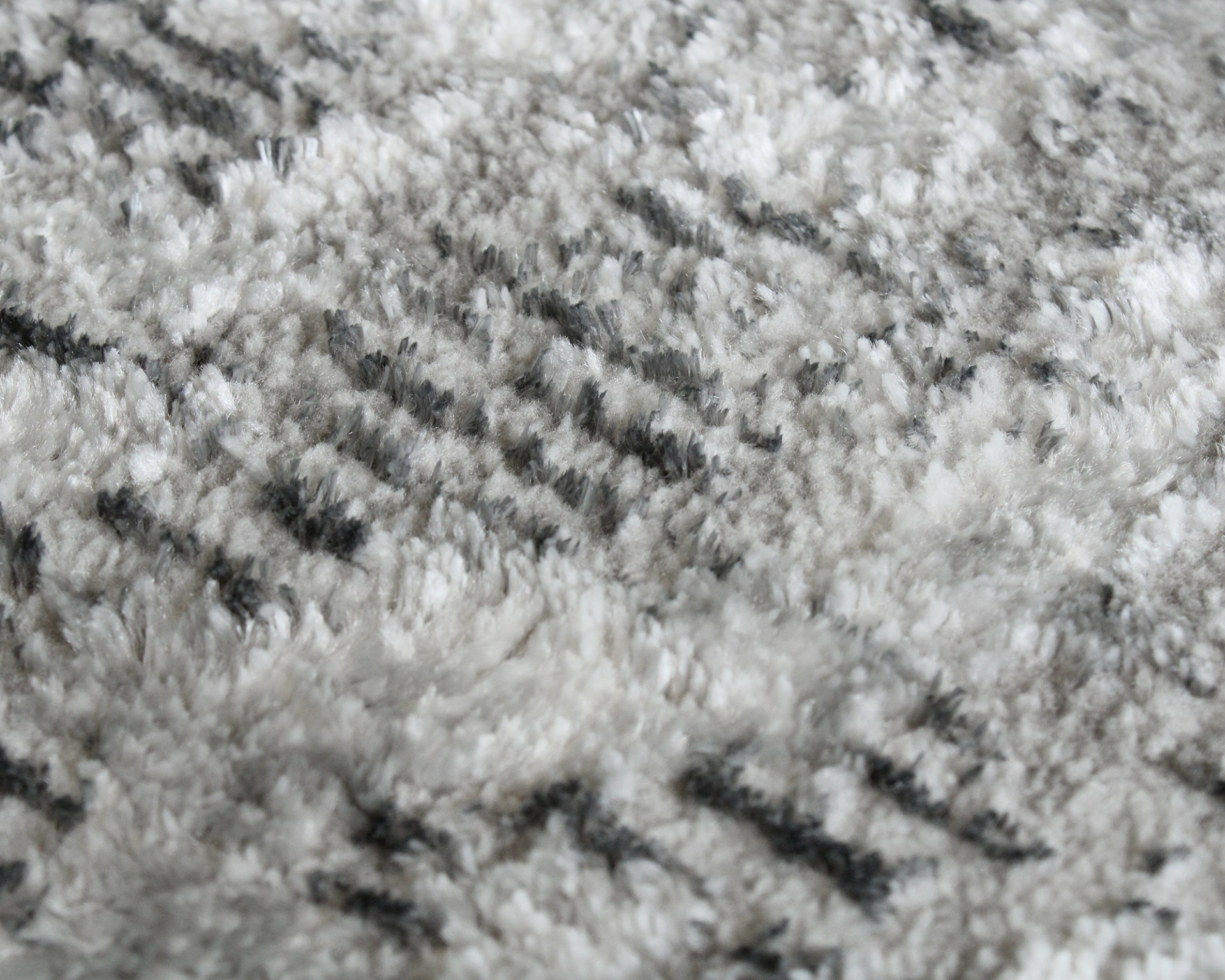Tapete felpudo cinza e branco com padrão abstrato preto