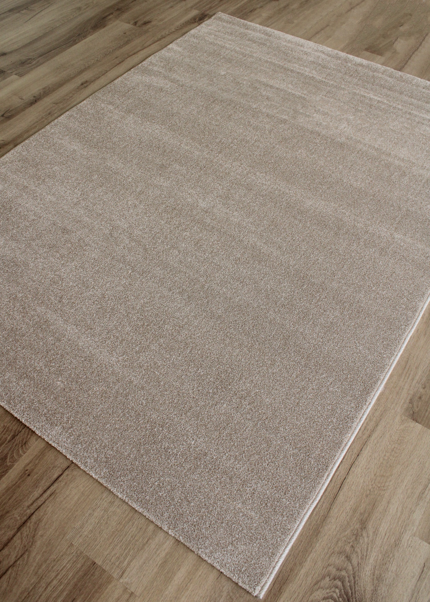 Tapete bege de pelo curto sobre chão de madeira clara