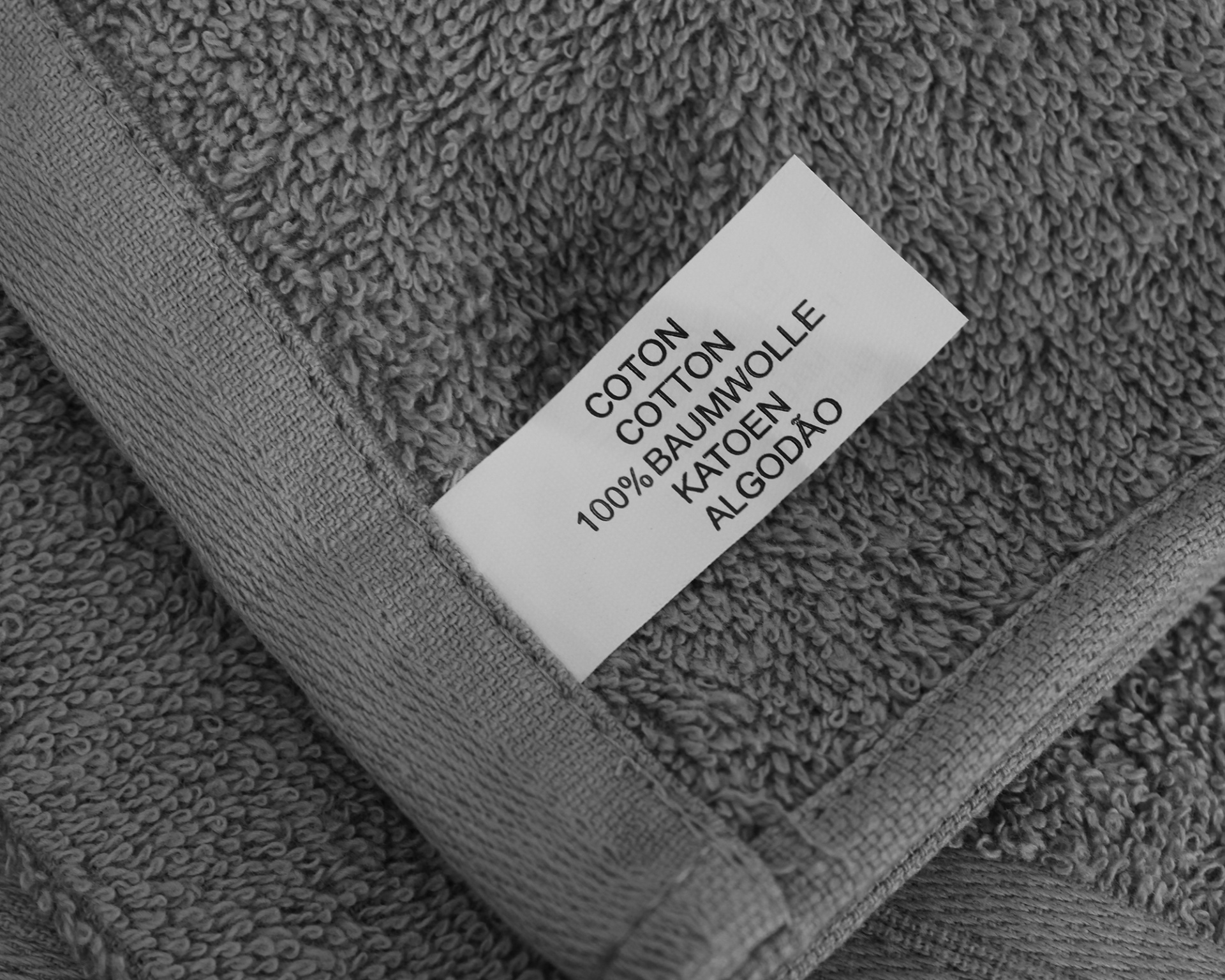 Etiqueta branca com texto em várias línguas numa toalha cinzenta