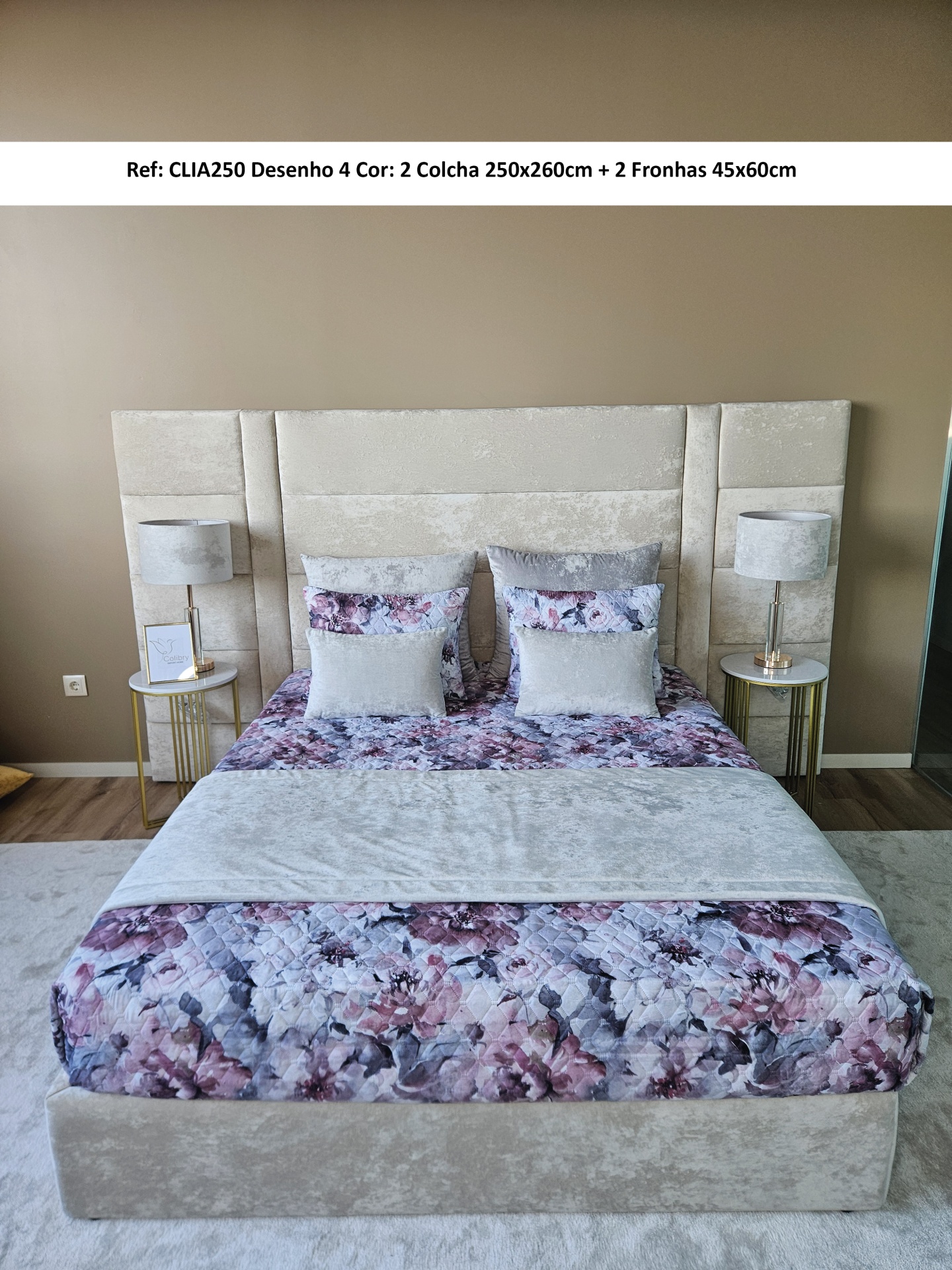 Cama com cabeceira cinza, colcha e fronhas florais roxas e cinza, mesas de cabeceira com abajures cinza