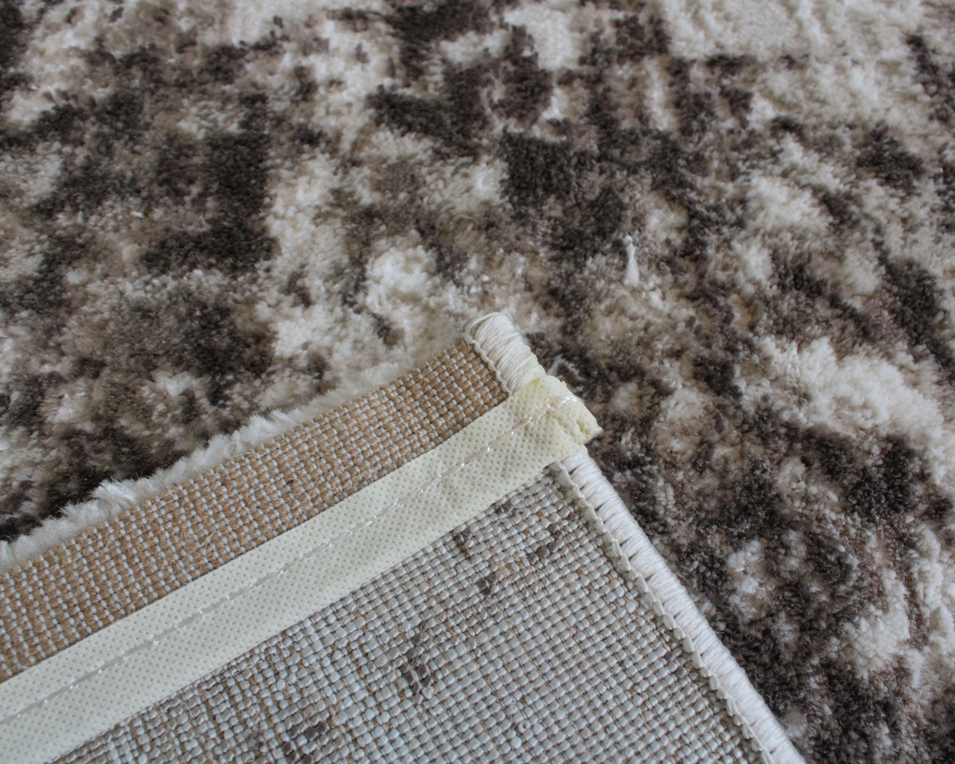 Tapete com padrão abstrato castanho e branco e parte inferior de tecido tecido bege com costura branca