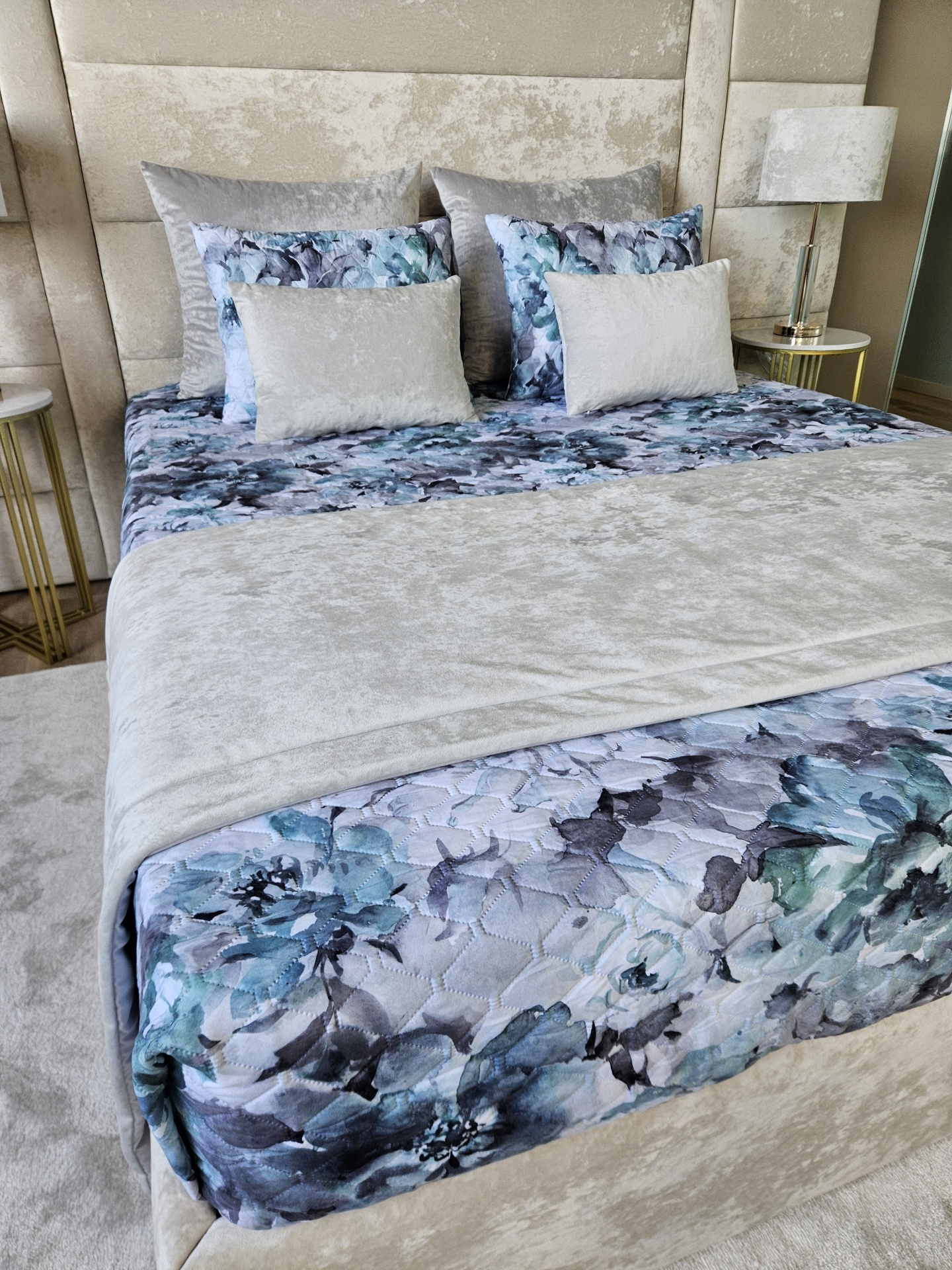 Cama elegante com roupa de cama floral e cinza aveludado numa decoração de quarto moderna