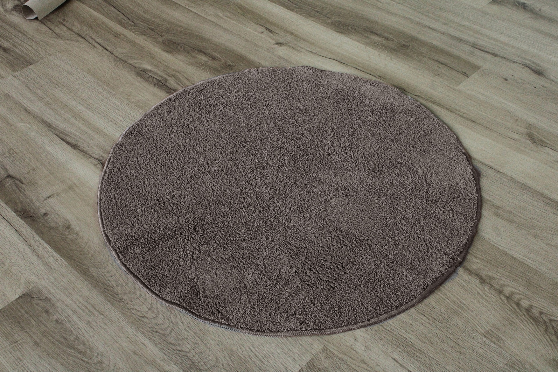 Tapete redondo cinza em chão de madeira clara