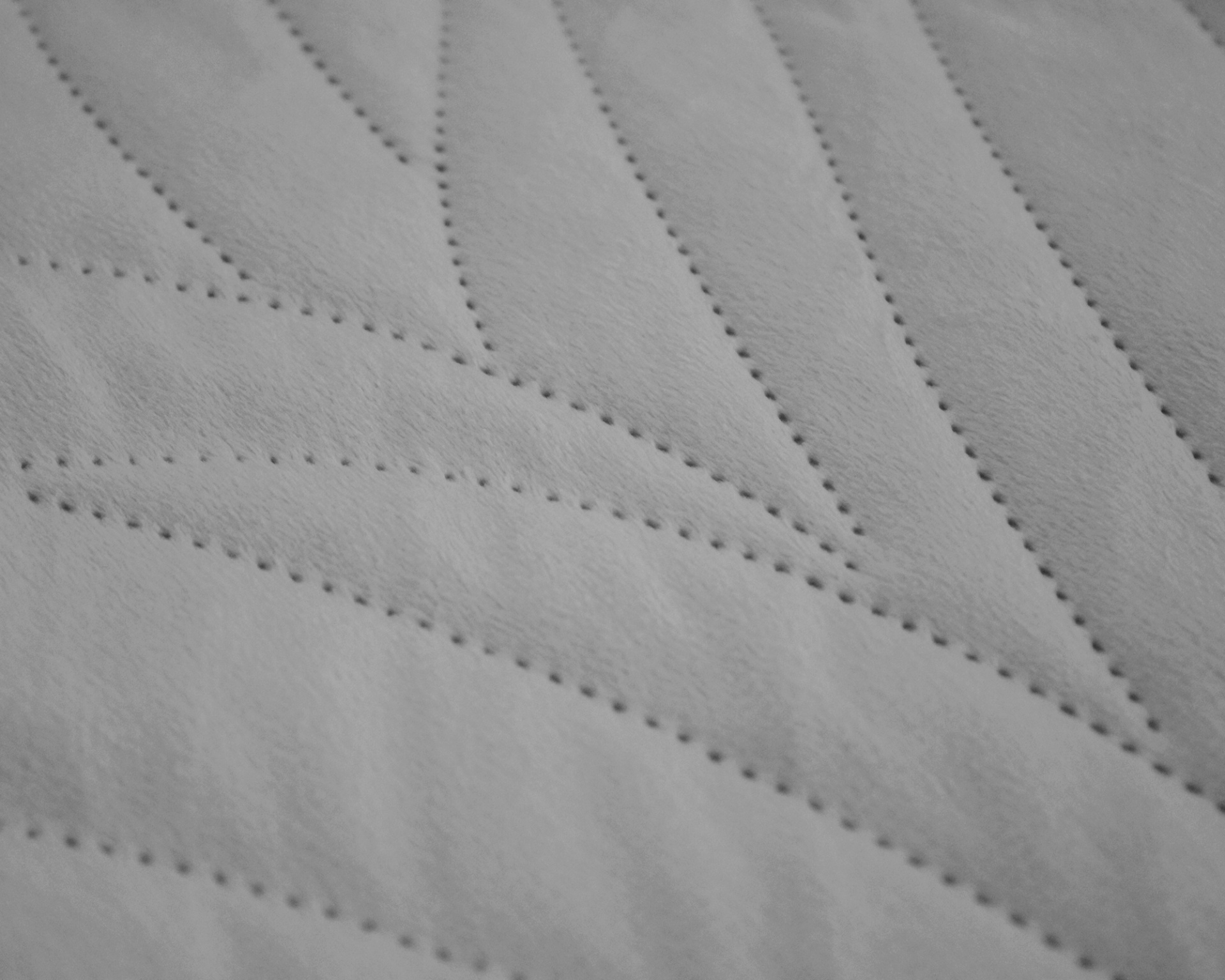 Tecido cinza claro com padrão ondulado e perfurações