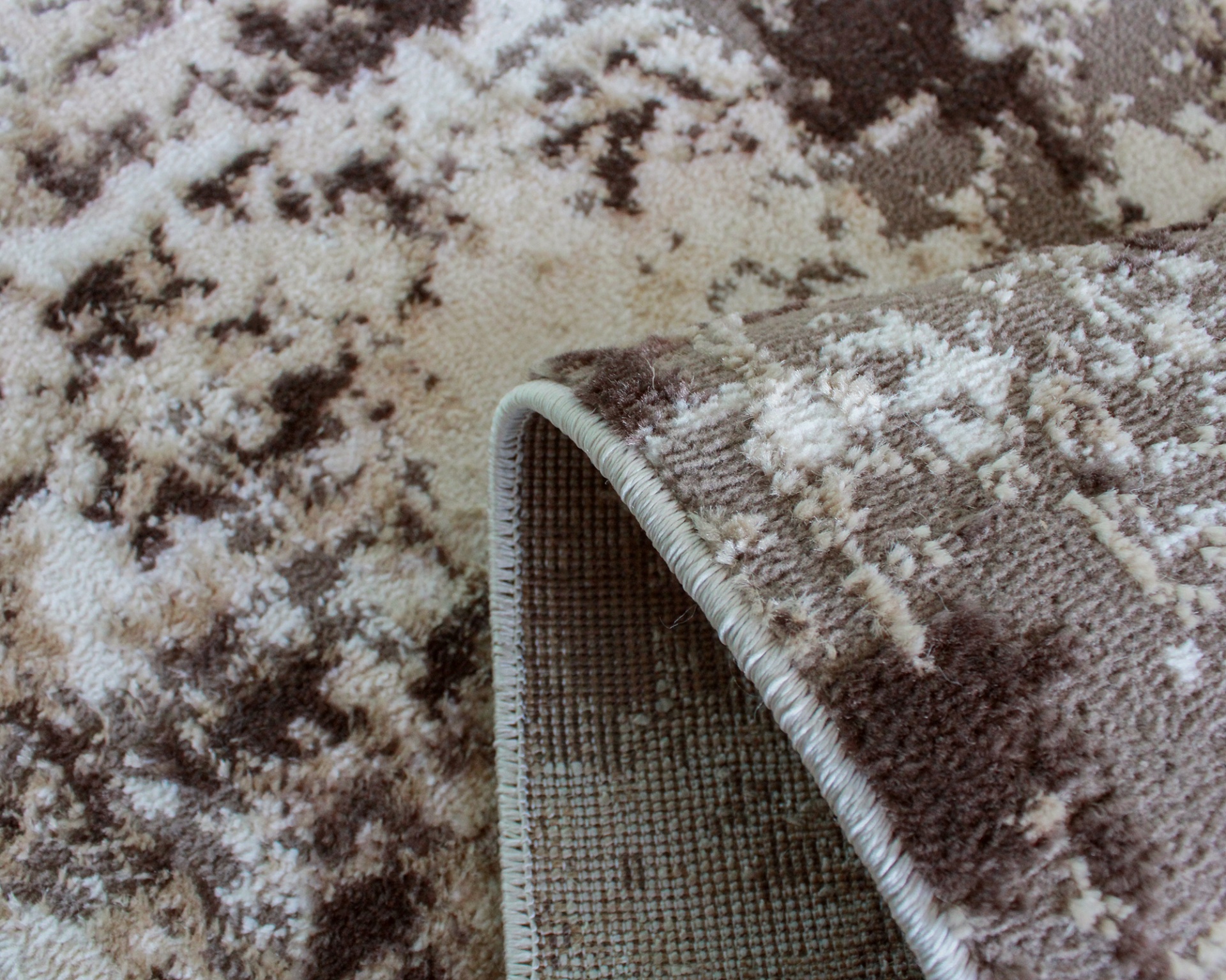 Tapete claro e castanho com padrão abstrato e borda costurada.